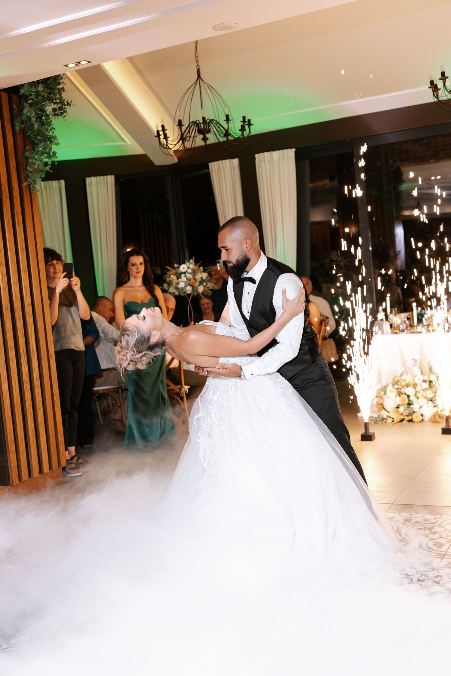 A couple dances their first dance at a wedding reception surrounded by romantic fog from a fog machine on the dance floor.