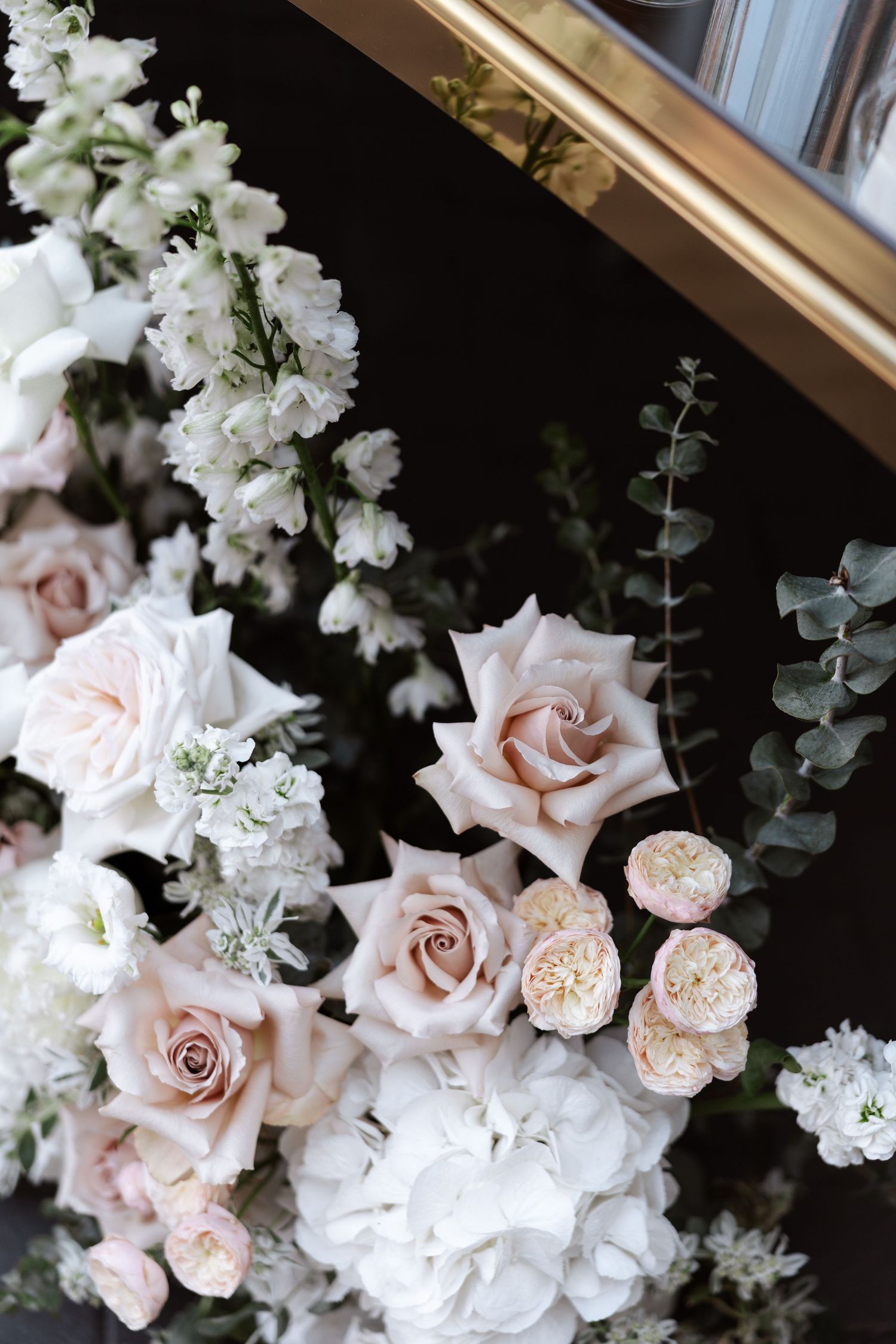 Delicate arrangement of blush pink roses and white flowers with eucalyptus for wedding decor.