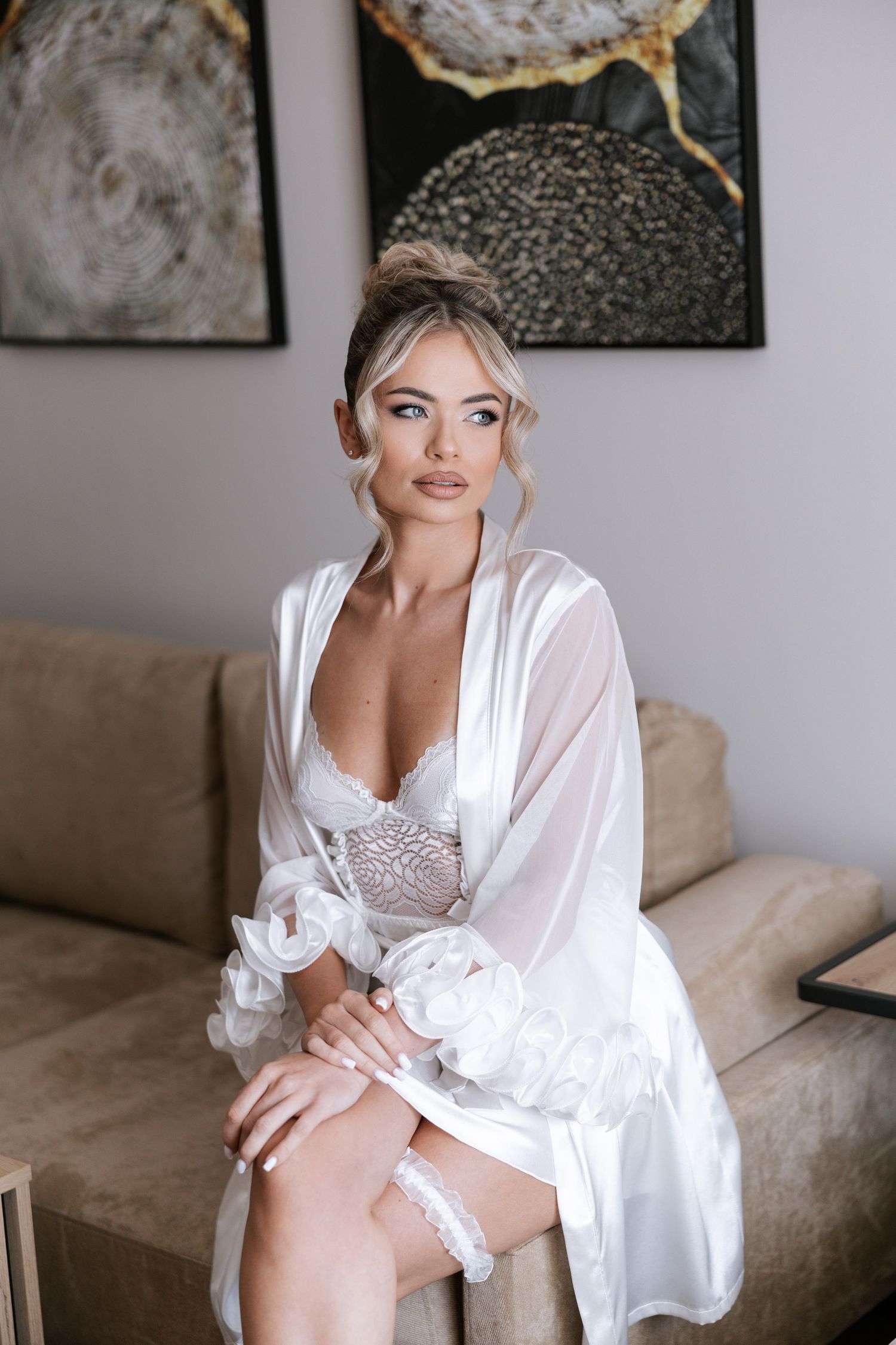 Elegant white silk robe with lace details photographed in a soft, romantic indoor setting.