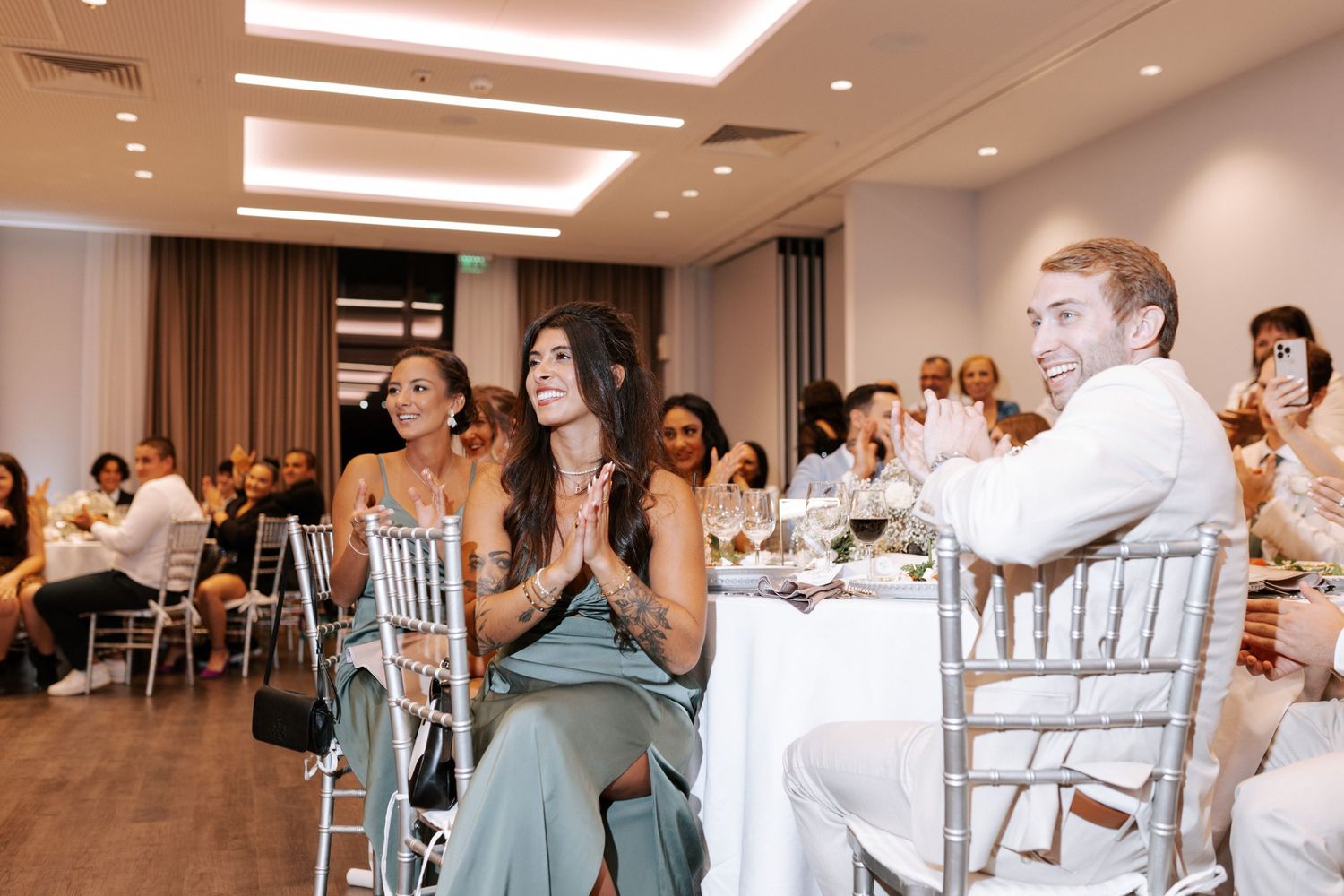 Wedding reception guests enjoying speeches in an elegant indoor venue.
