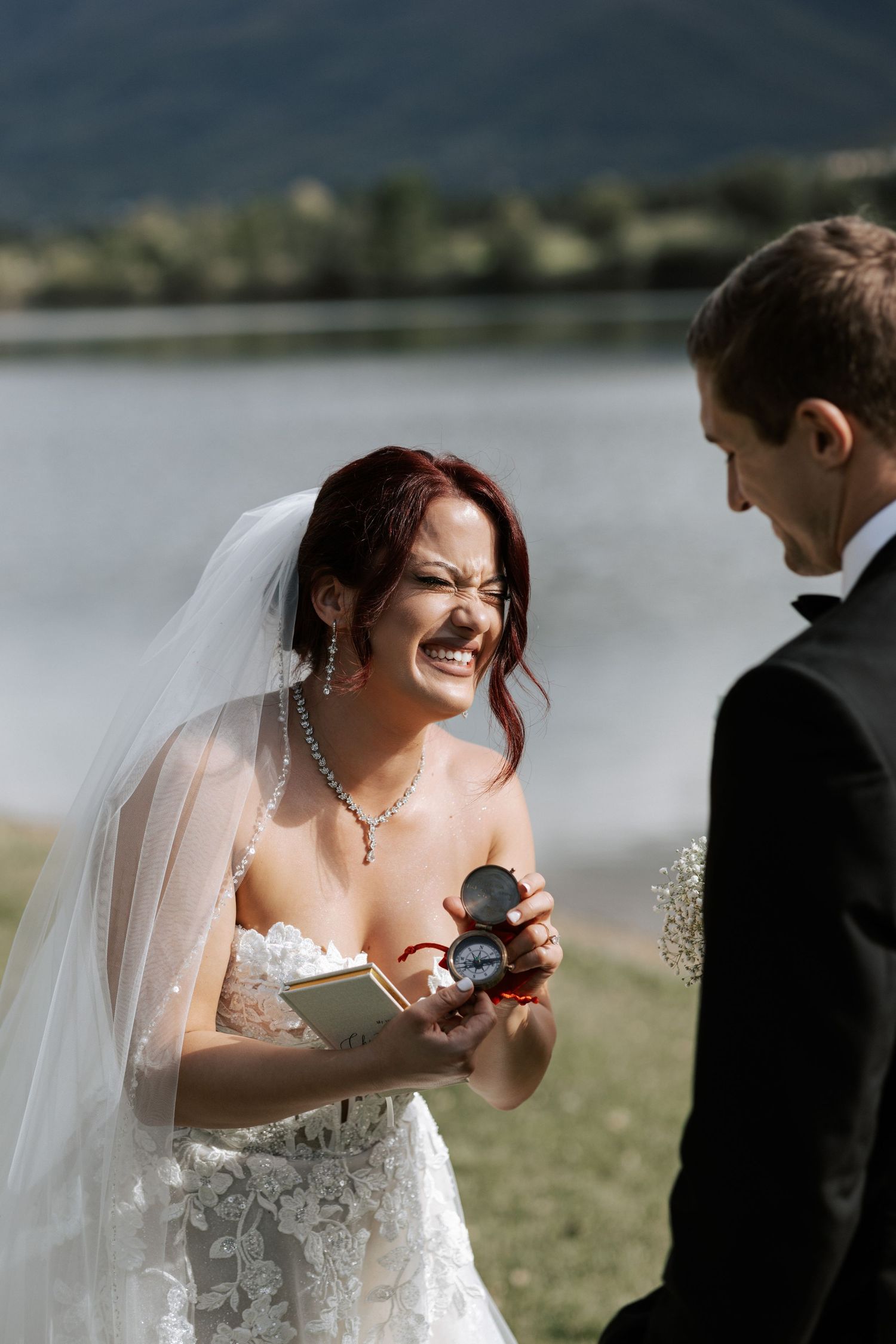 A candid moment of laughter during the exchange of wedding vows by the lake.