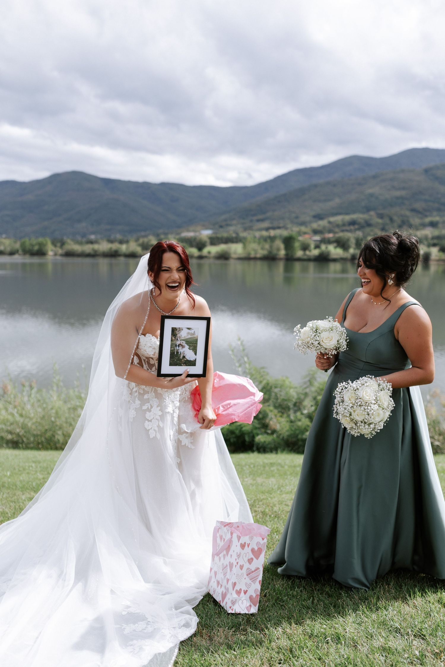 Wedding pair looking at framed photo during lakeside gift opening moment.