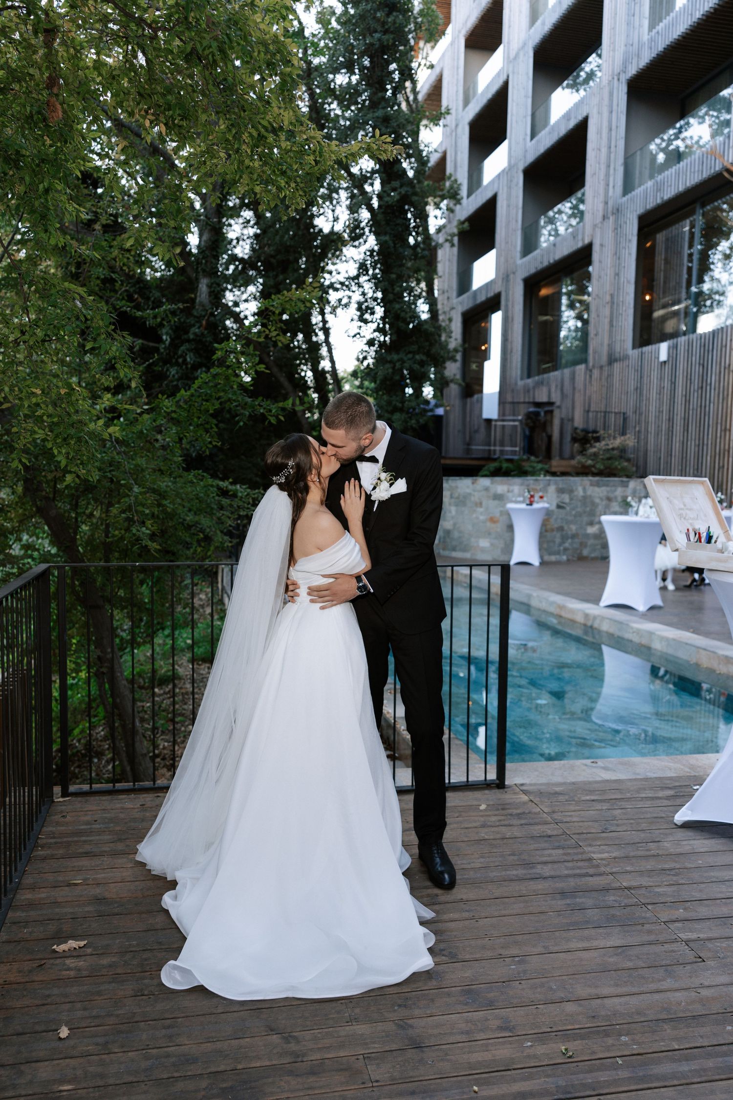 Couple sharing romantic moment by pool during wedding photoshoot.