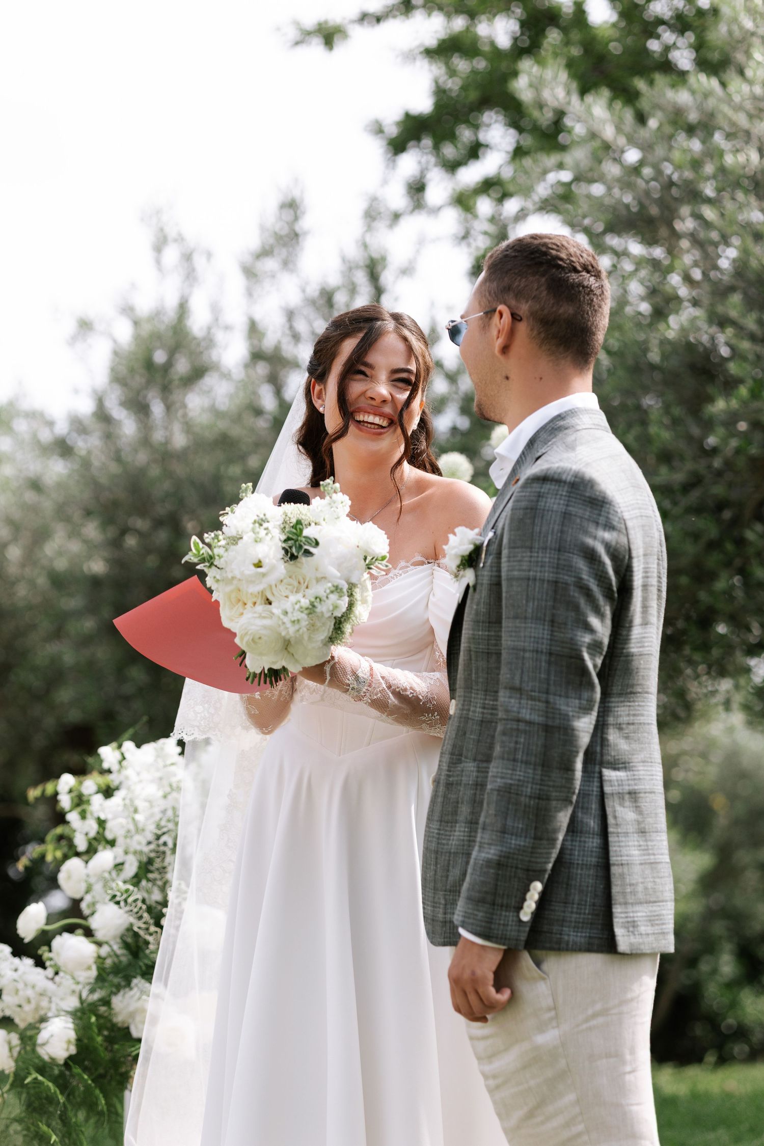 Romantic wedding couple shares tender moments in an outdoor garden setting with white floral bouquet.