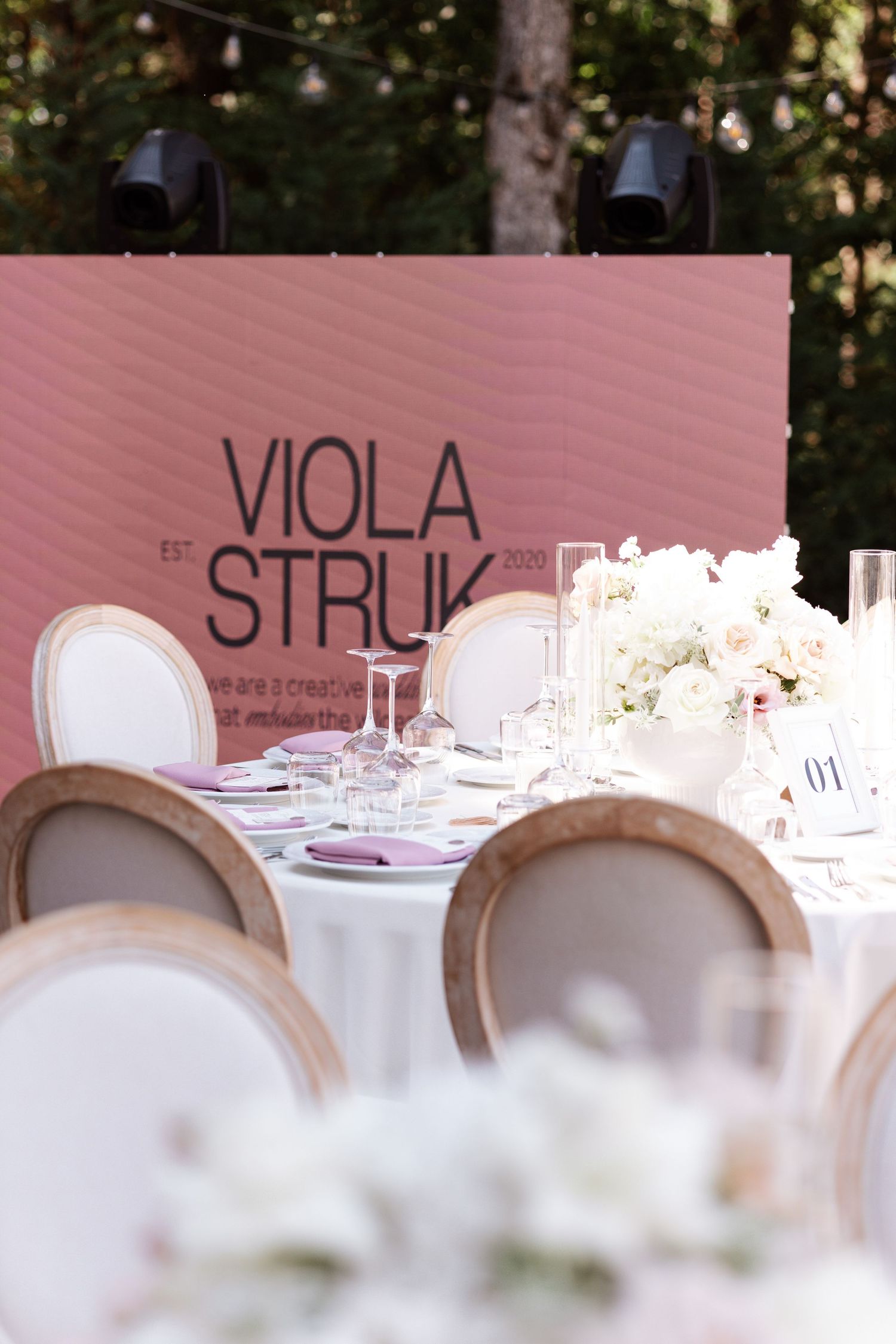 Wedding reception table settings with elegant place cards and white floral centerpieces.