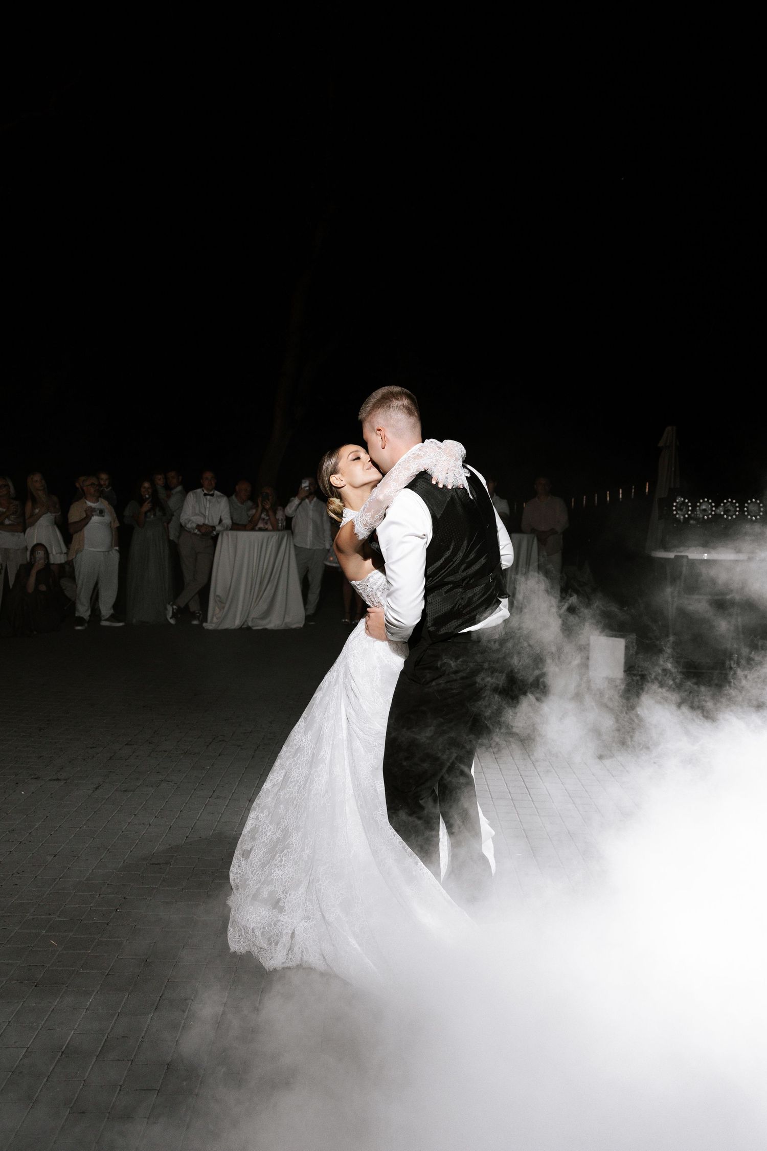 First dance with dramatic fog effect on dark dance floor at wedding reception.