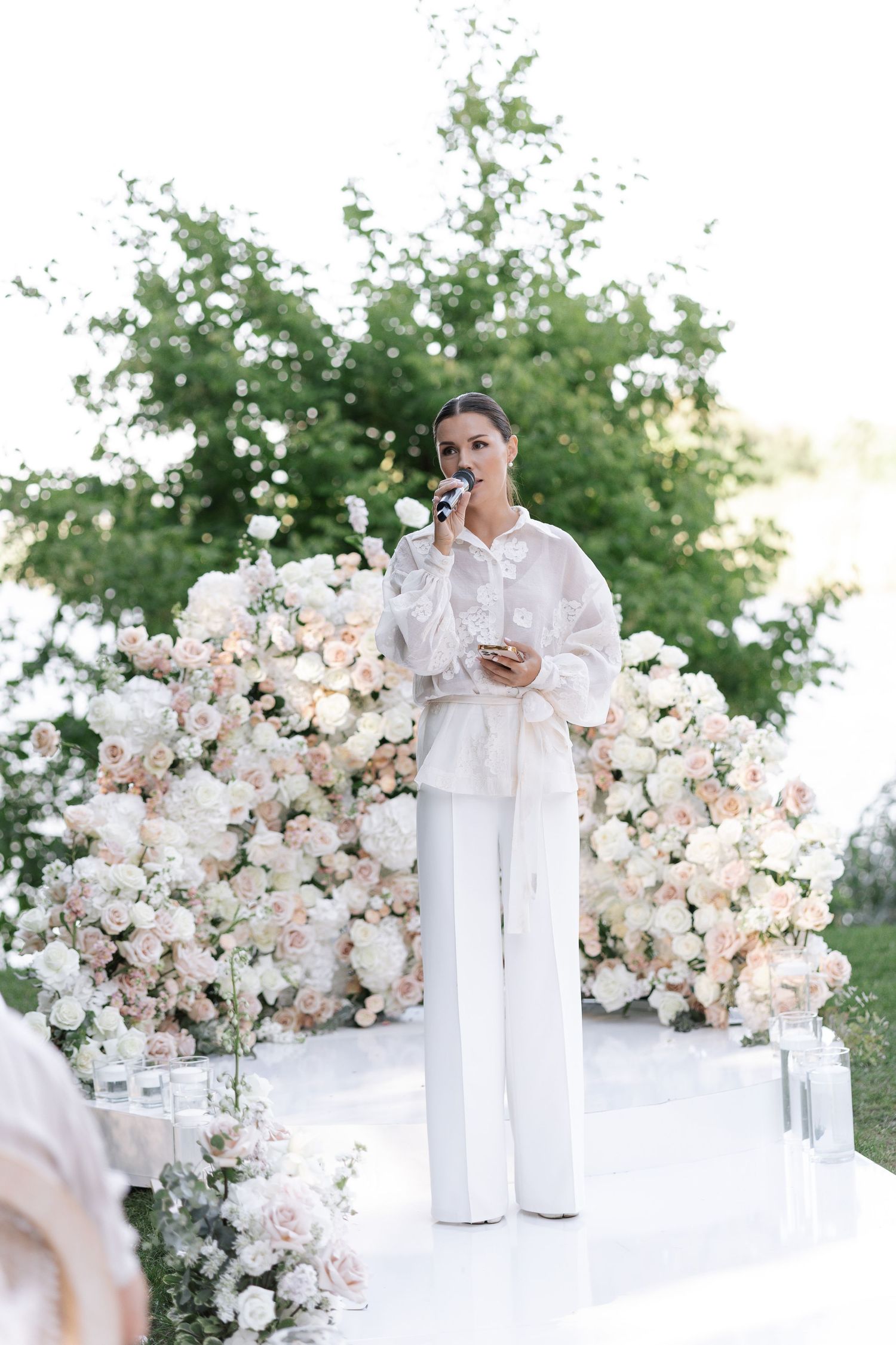 Elegant outdoor wedding setup with white floral arrangements and pedestals.