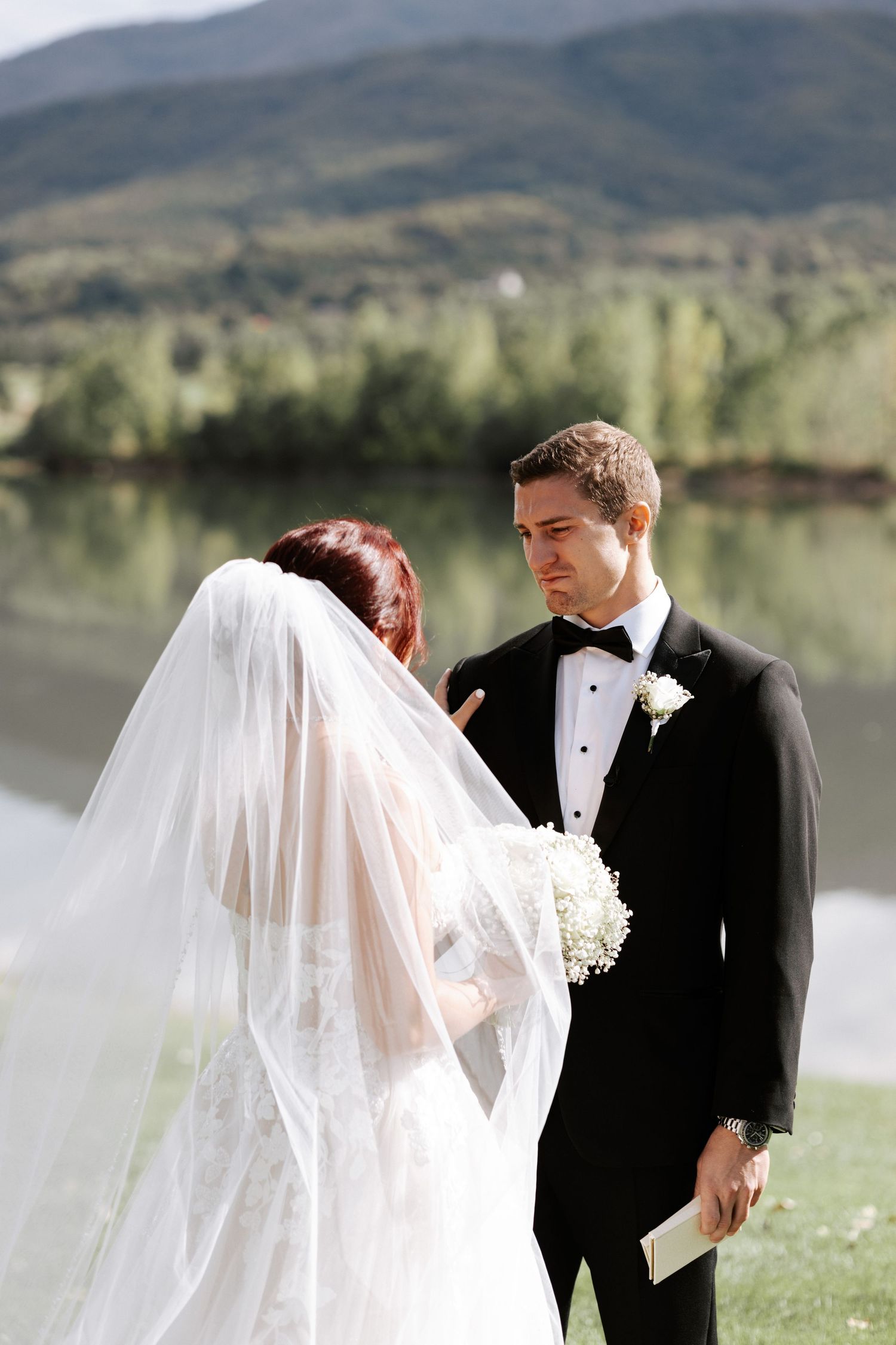 A wedding couple exchanges vows against a scenic mountain lake backdrop.