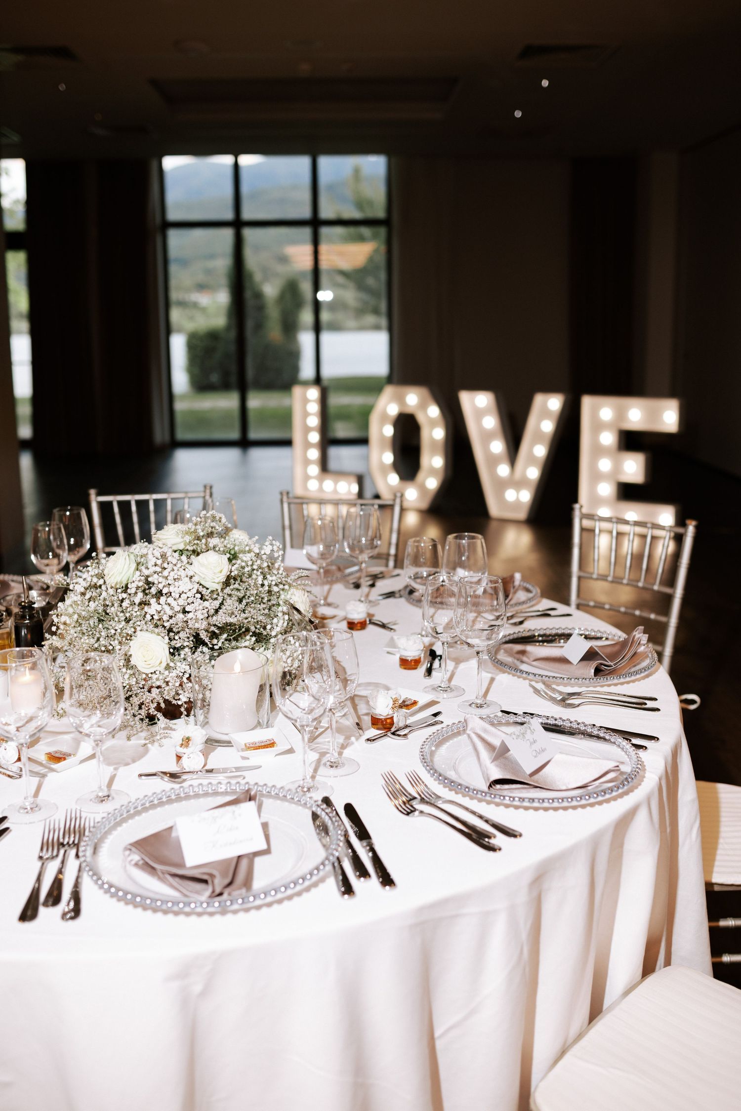 Wedding reception table with illuminated LOVE sign and baby's breath centerpieces.