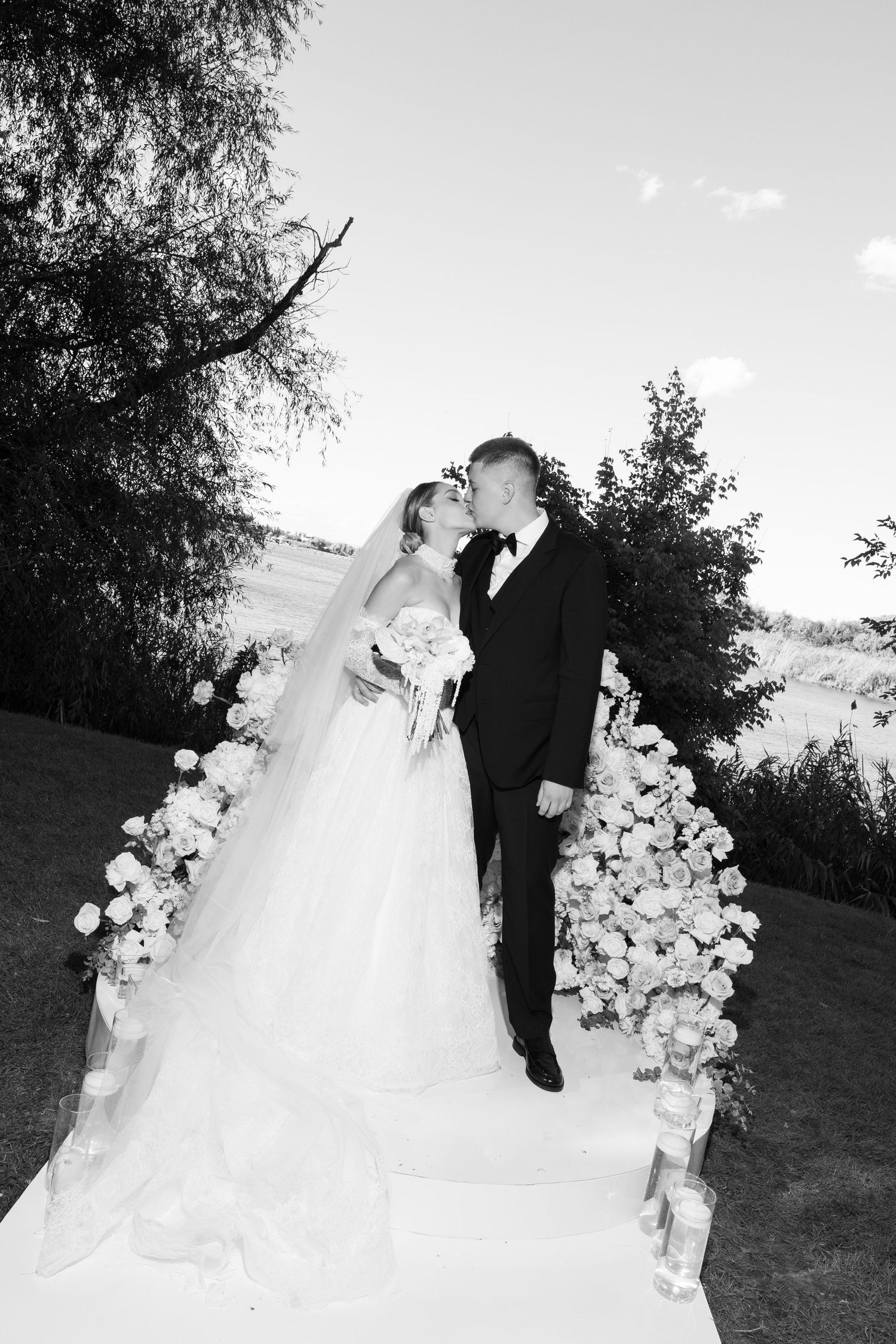 Black and white wedding photos with floral arch decorations in an outdoor setting.