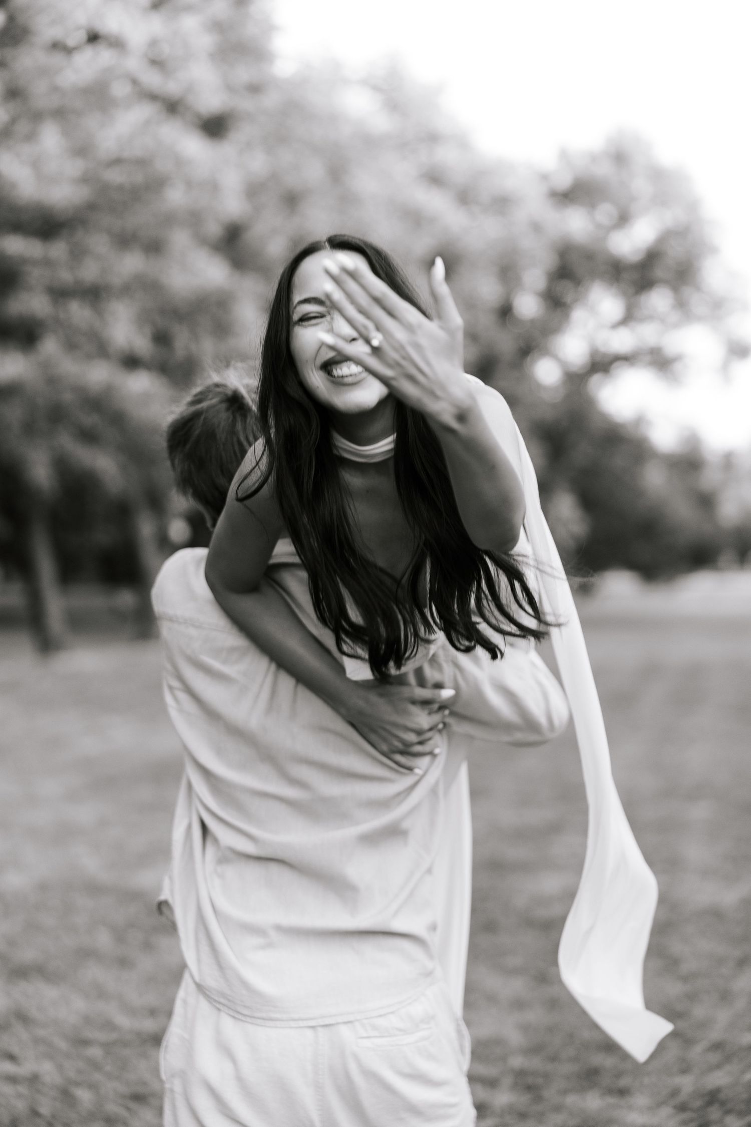 A person in a white sweater laughs and moves playfully in a black and white photo sequence outdoors.