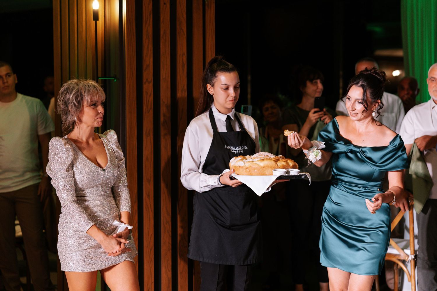 Couples dancing together at a wedding reception in a dimly lit venue with warm lighting.