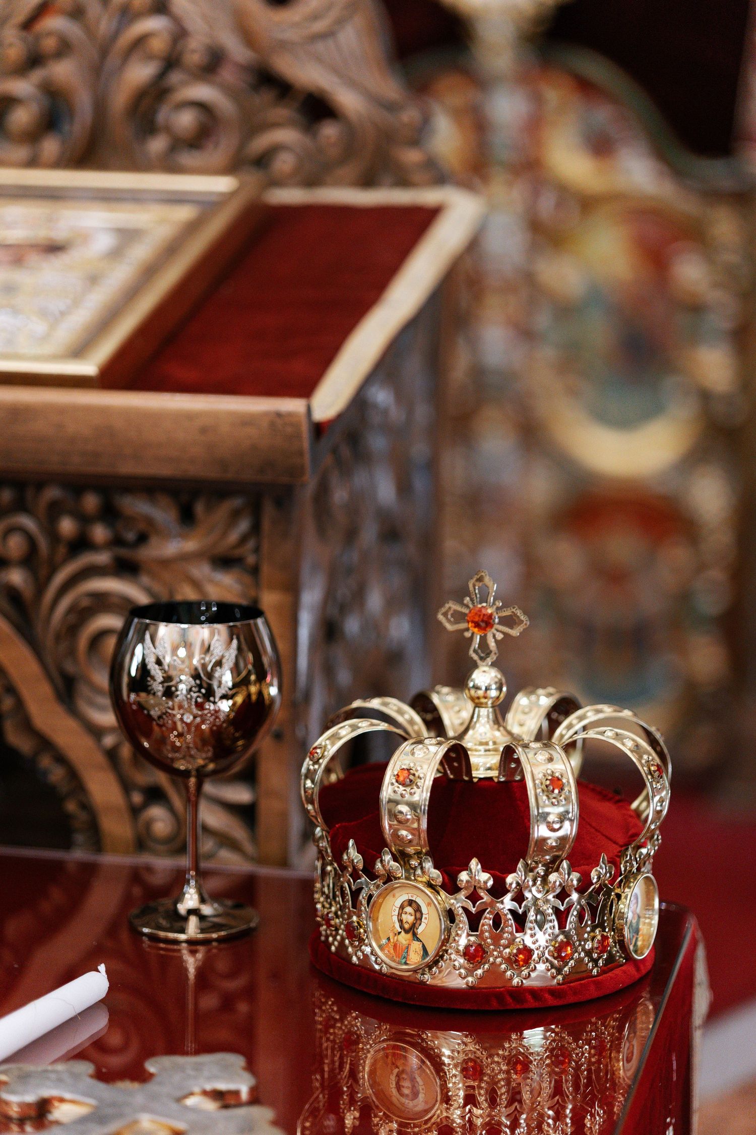 Ornate gold and silver royal crowns with jewels and intricate metalwork displayed on red velvet cushions.