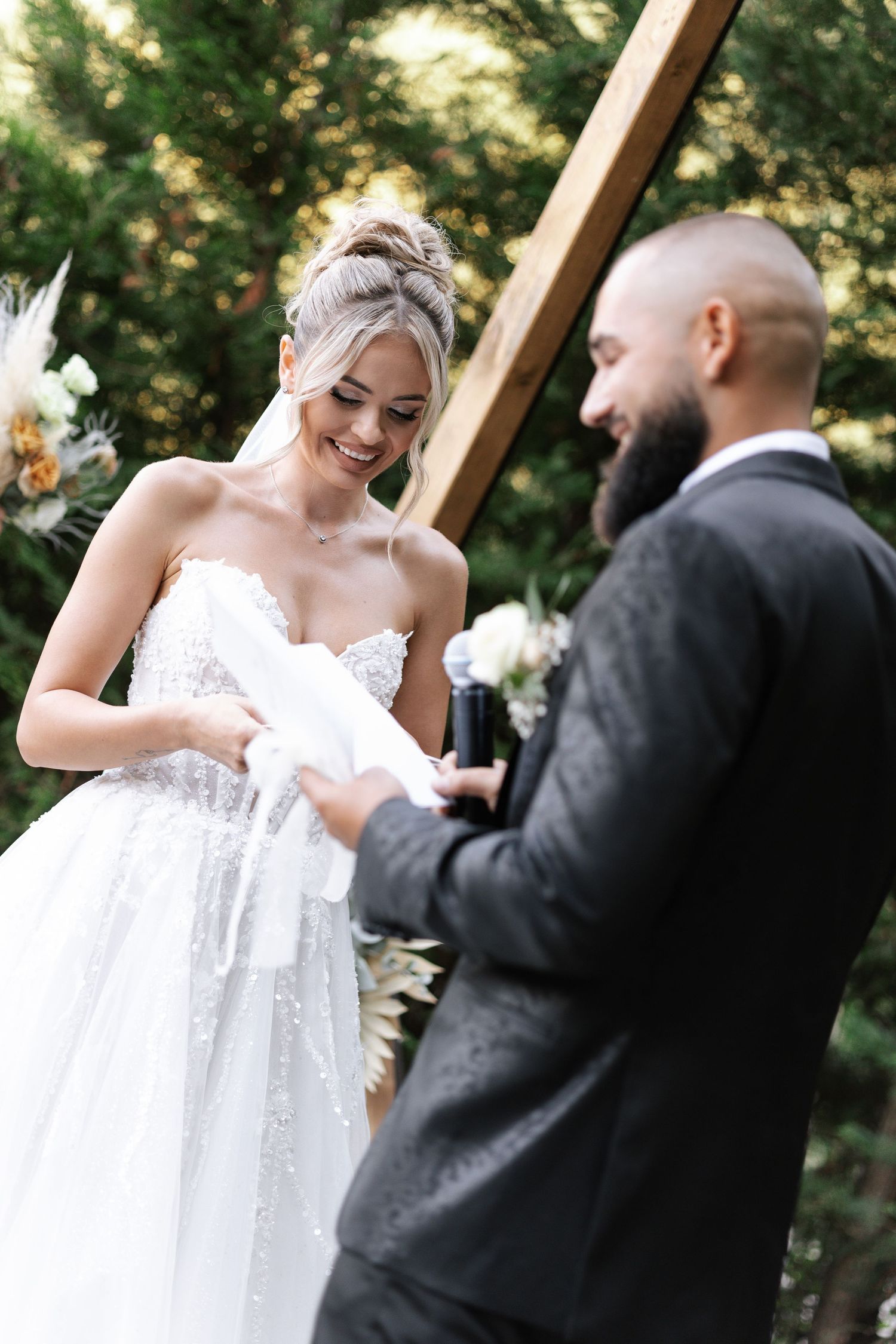 Candid outdoor wedding moment captured in a sunlit garden setting with flowing white dress.