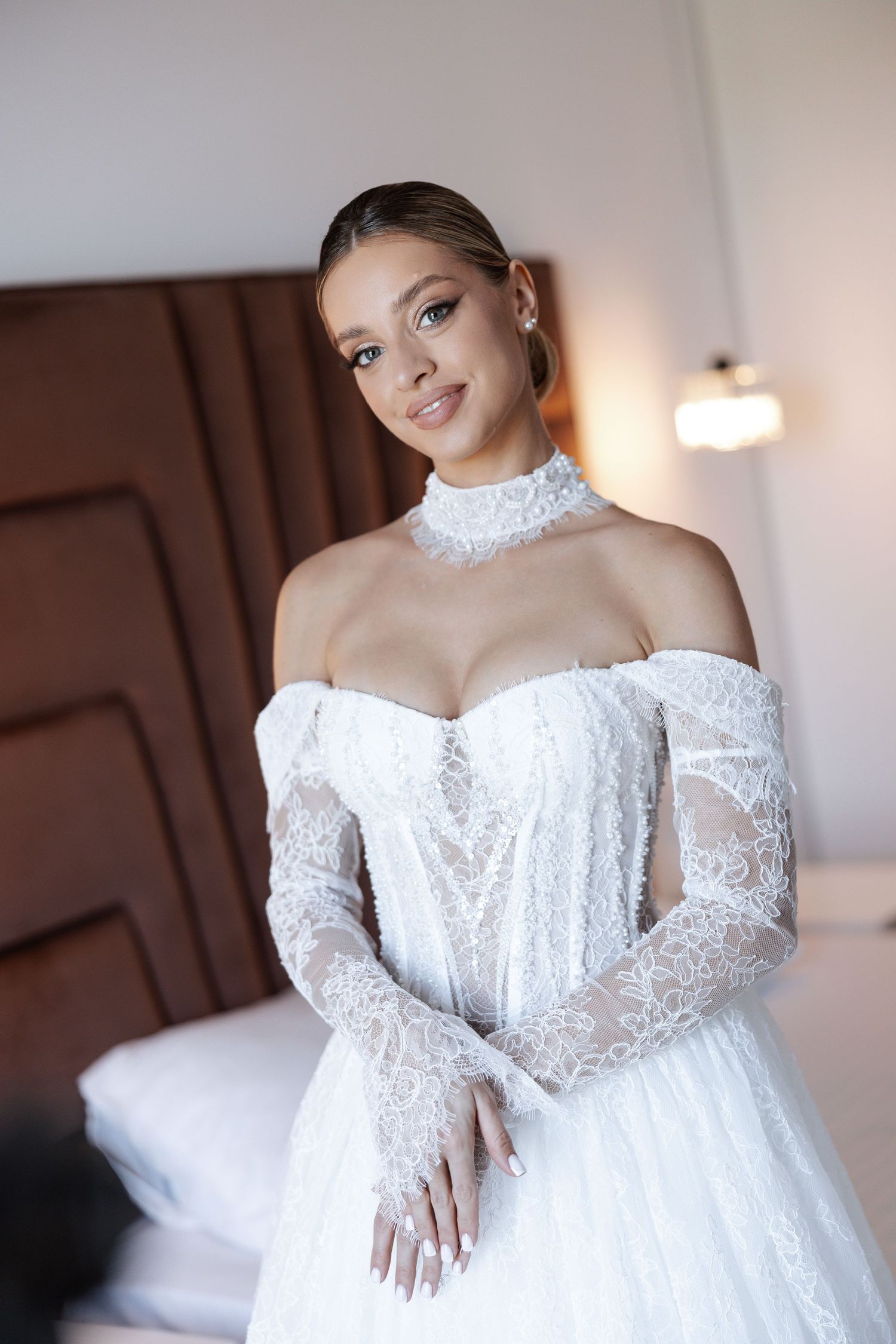 Bride wearing off-shoulder lace wedding dress with high neck choker detail.