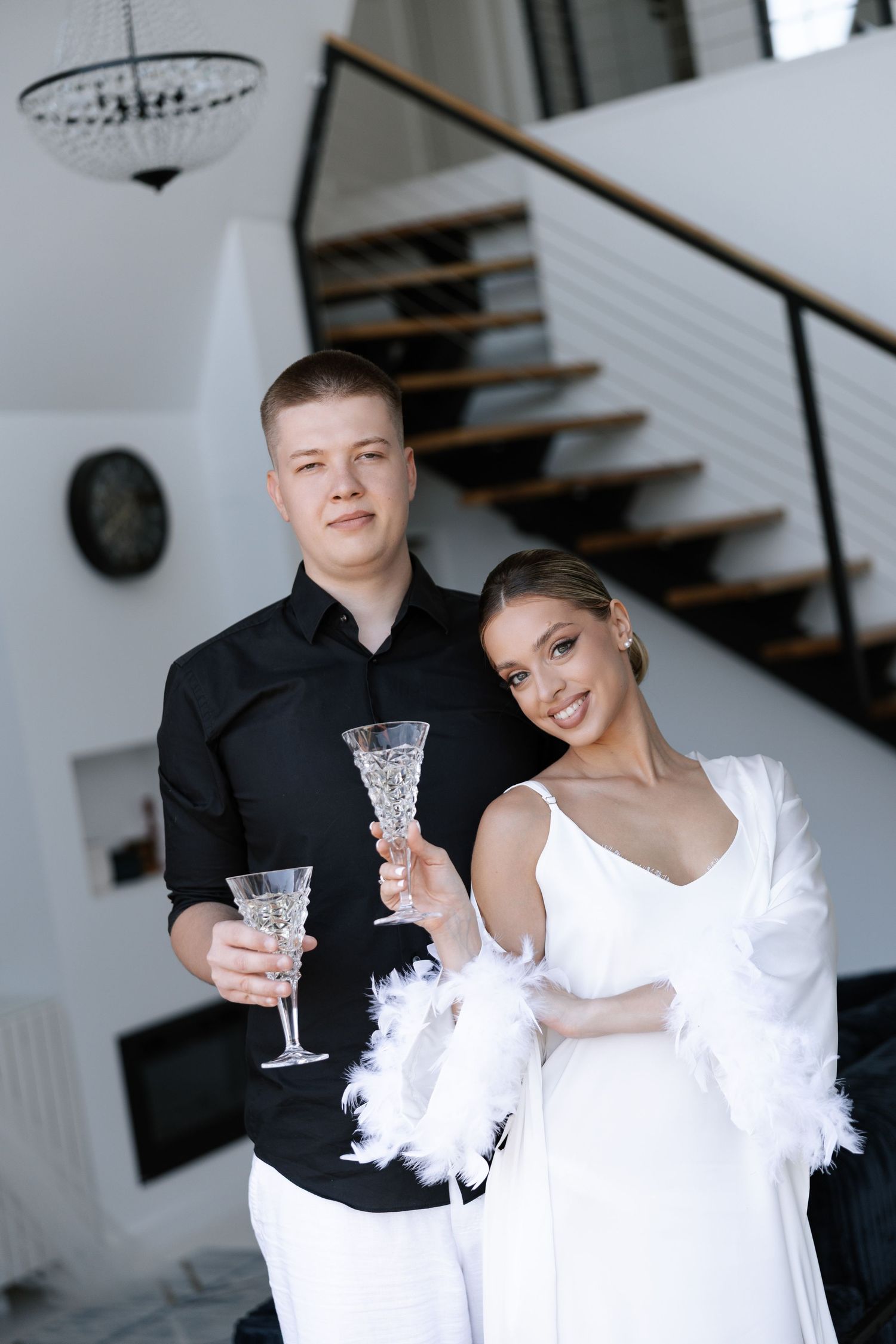 Elegant couple in black and white attire holding crystal glasses during a celebration.