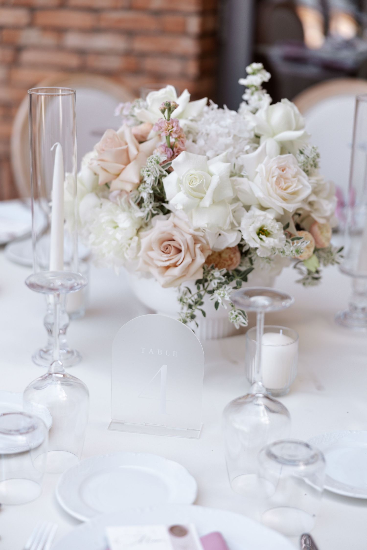 Elegant table setting with blush and white roses in crystal vases at a wedding reception.