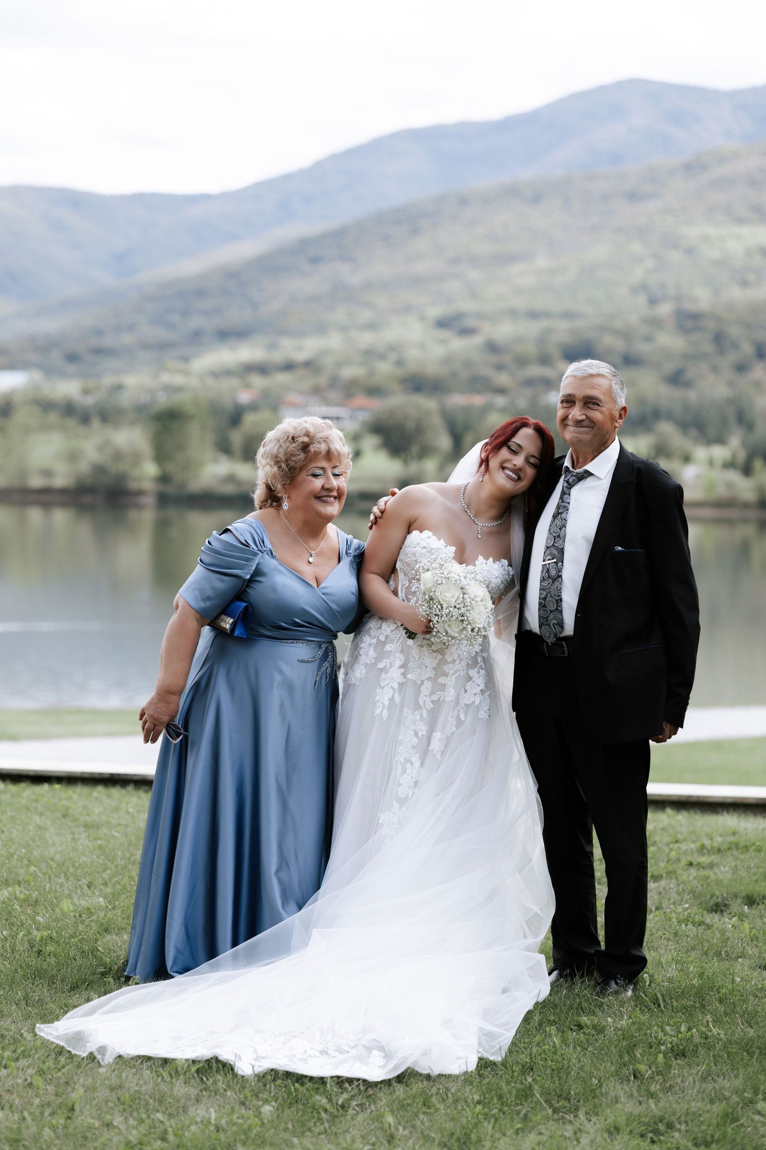 A beautiful wedding portrait by a mountain lake with a bride in a lace gown.
