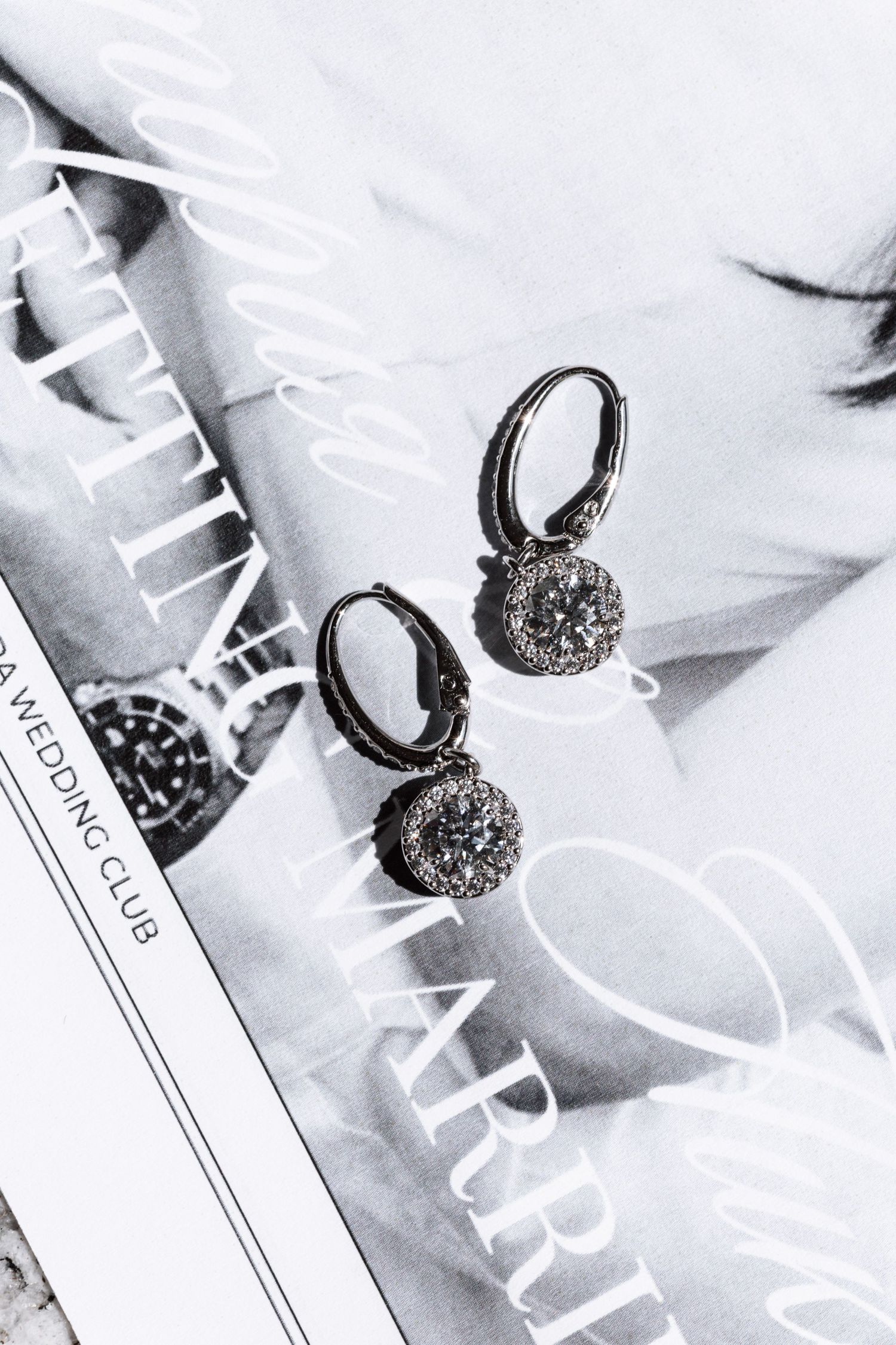 Elegant silver jewelry pieces with dark crystals displayed on white paper against a light background.