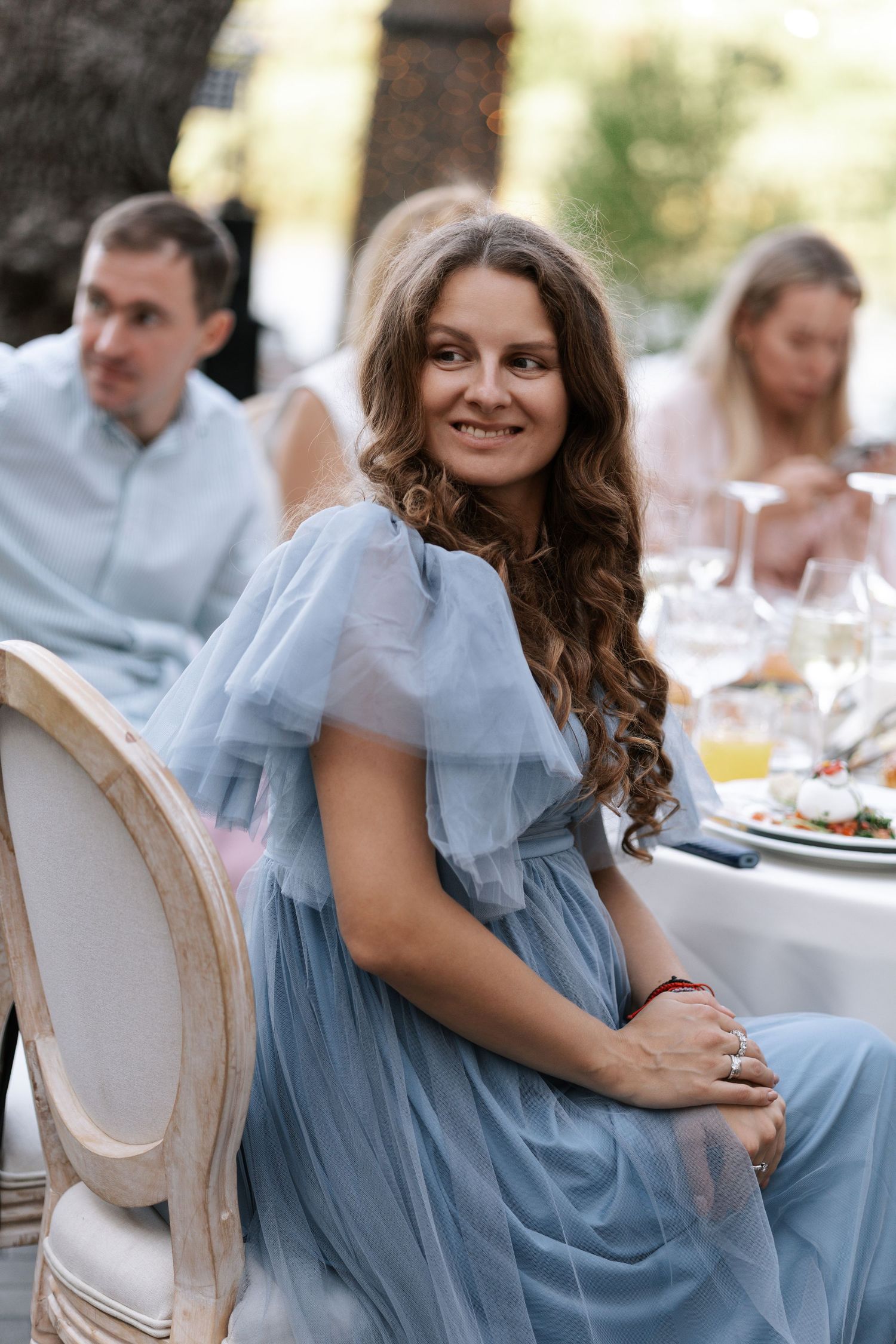 Wedding attendee in a flowing blue dress seated at an elegant reception table.