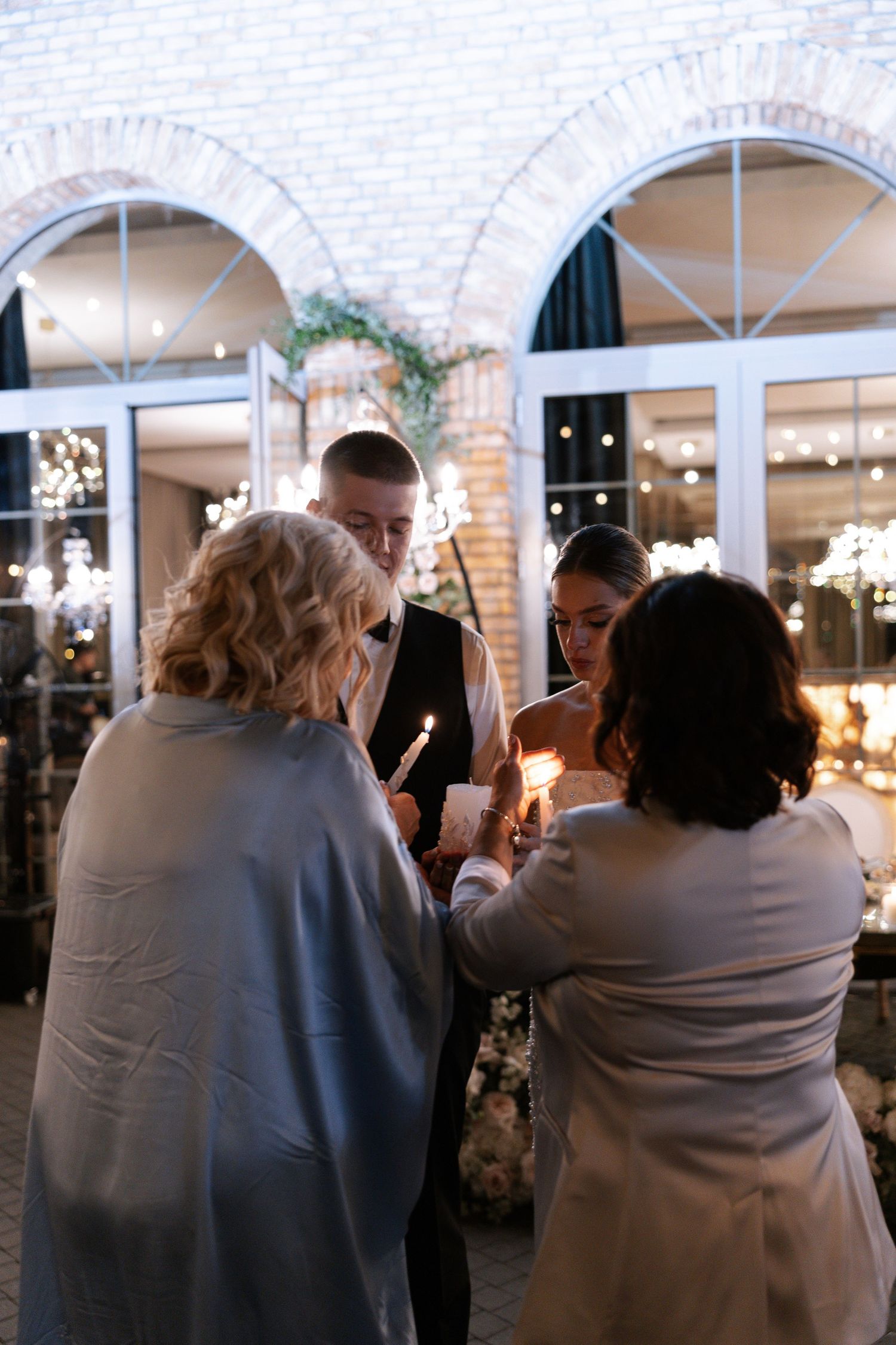 Wedding guests watch from chairs in a brick-walled venue space.