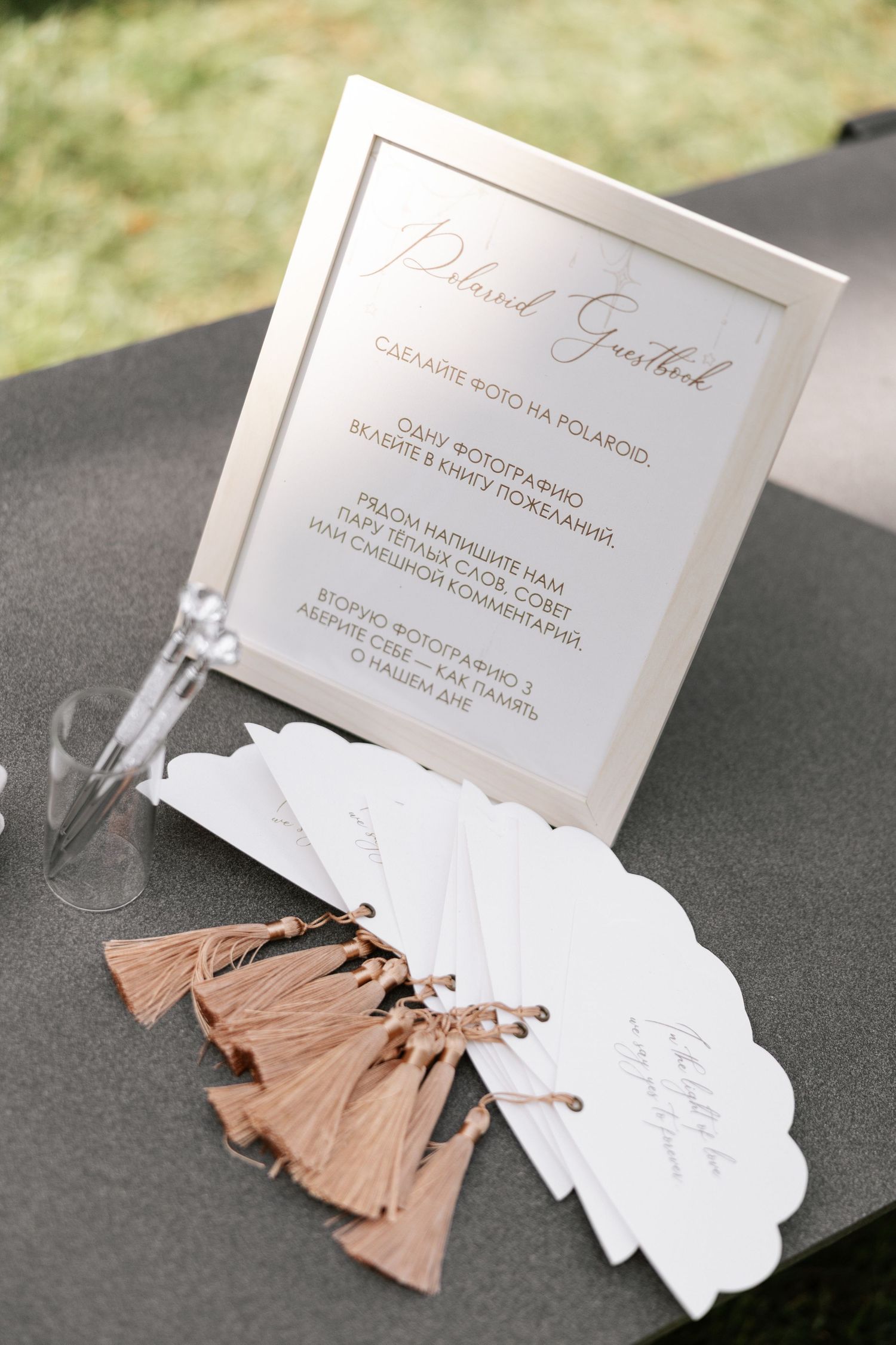 Wedding details card with rose gold tassels displayed on dark surface.