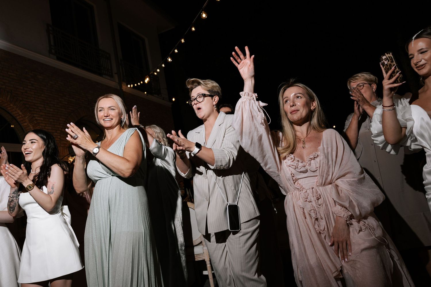 Wedding guests dancing and celebrating at an evening reception.