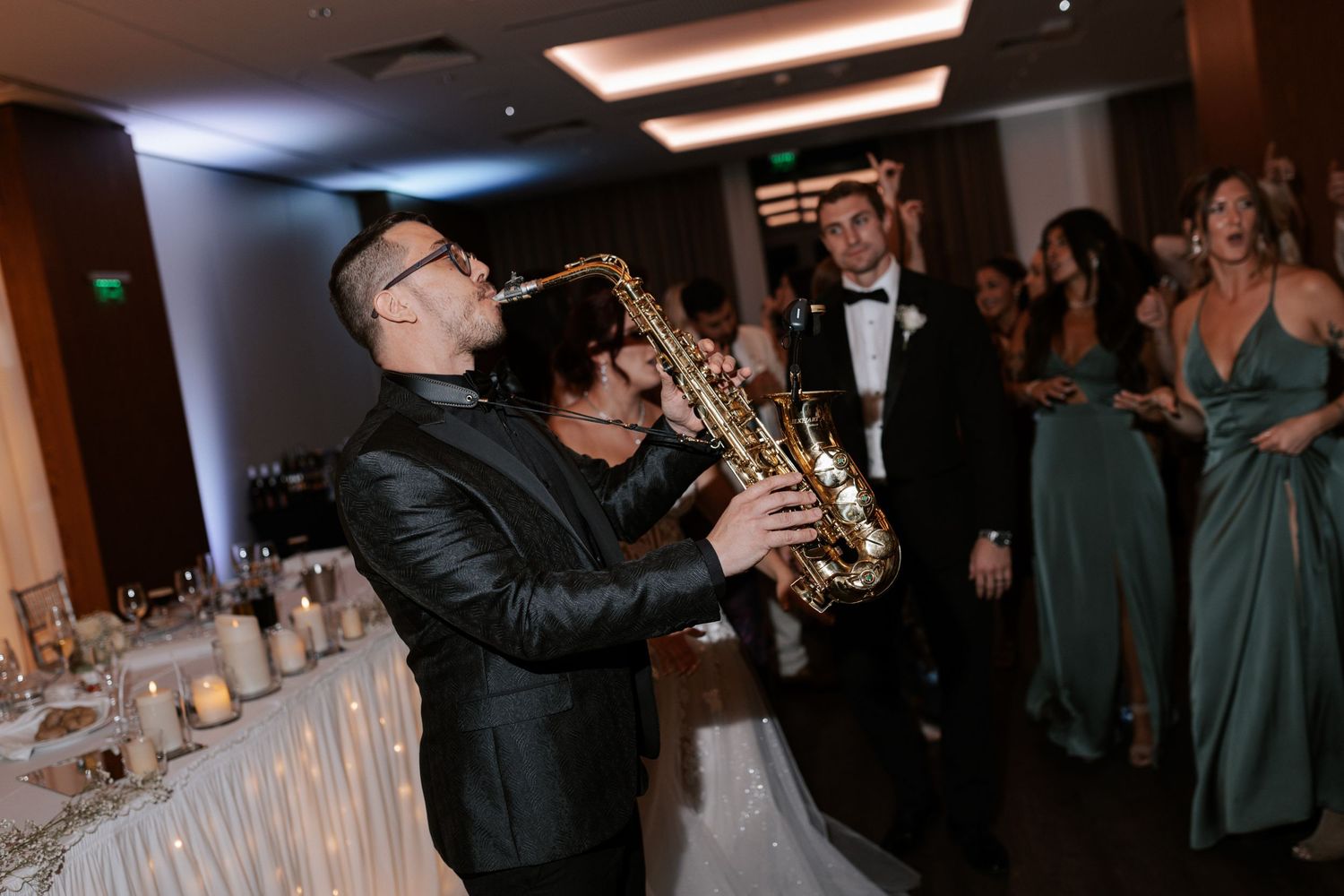 Saxophone player performs in formal attire at wedding reception.