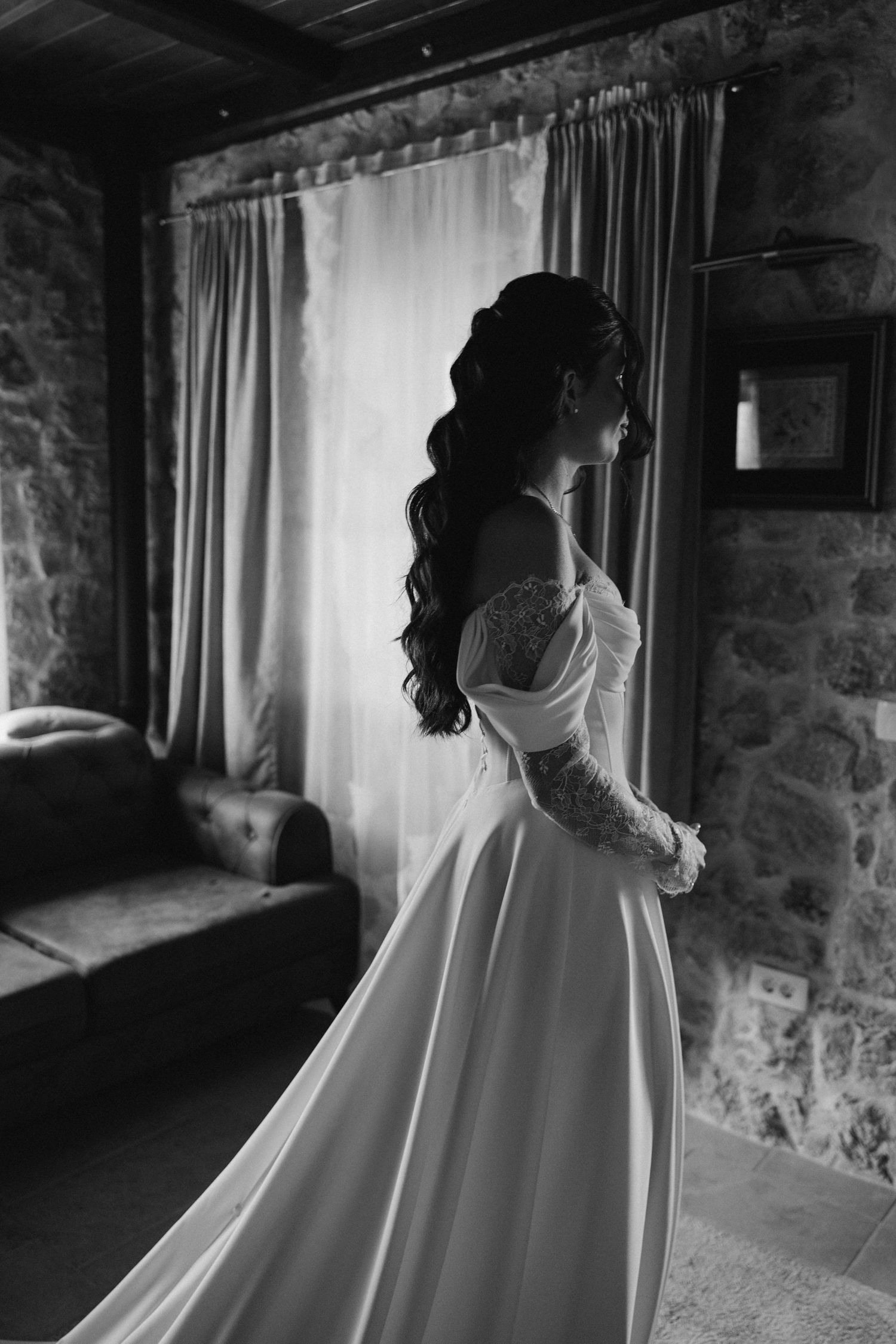 A black and white photo series shows a bride in a flowing white gown by a stone wall and window.