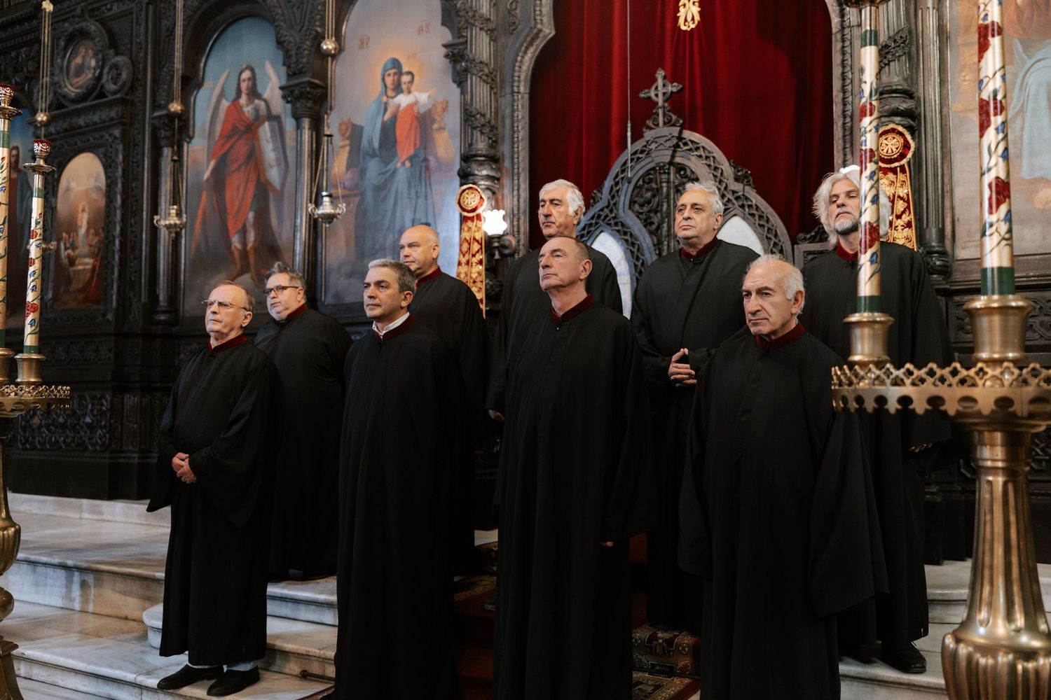 Choir members in black robes singing during orthodox church service.