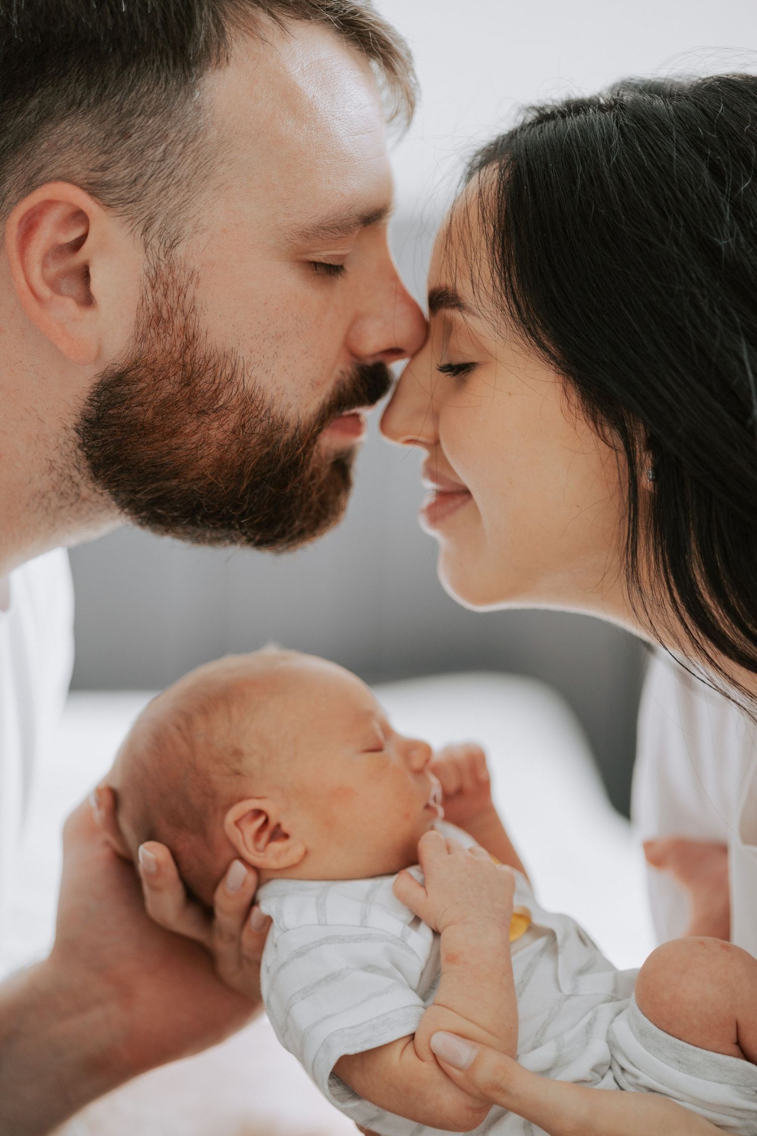 Intimate family moment with a newborn baby being held between two loving parents.