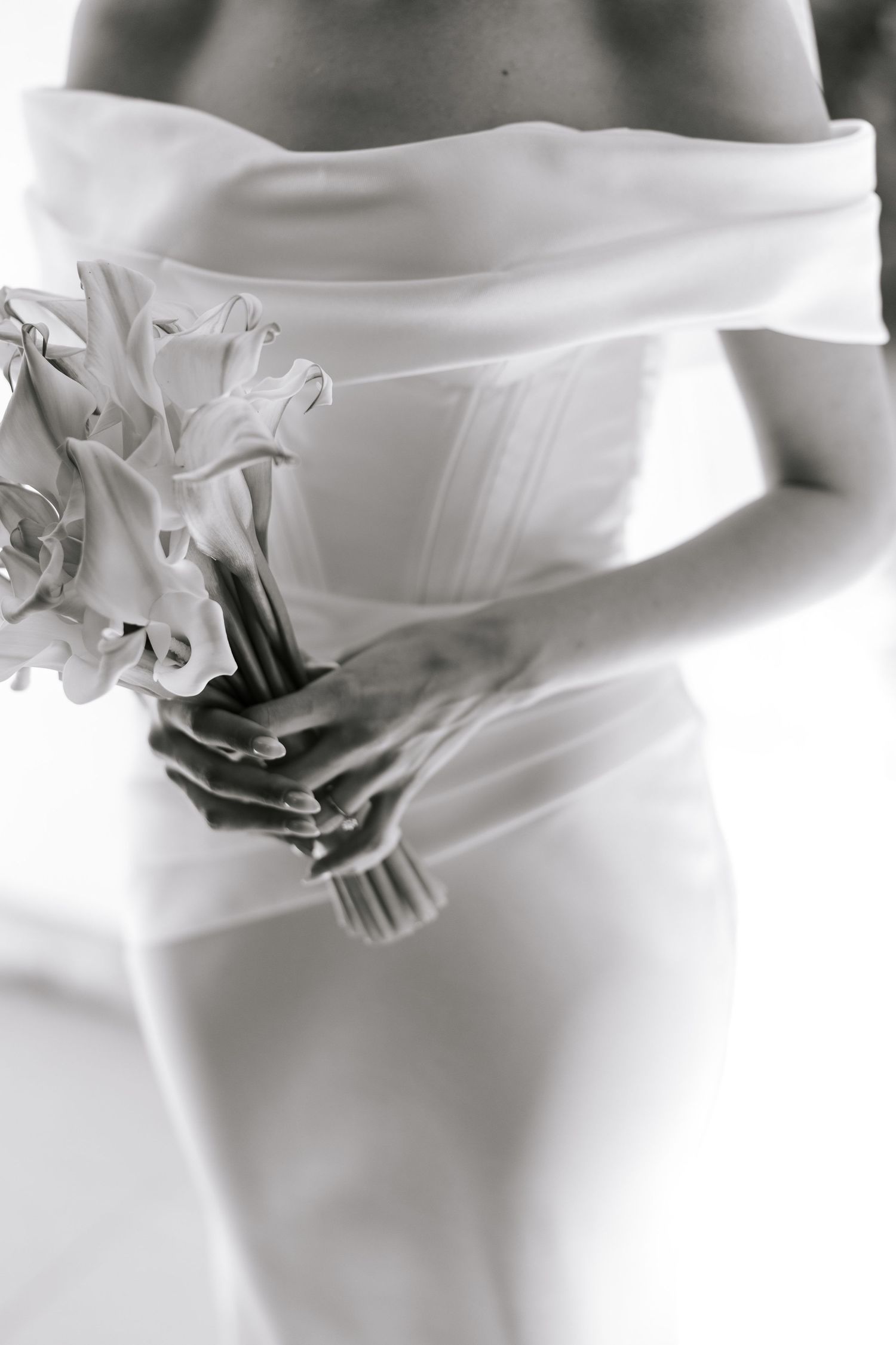 Close-up of a white wedding dress and bouquet in elegant black and white photography.