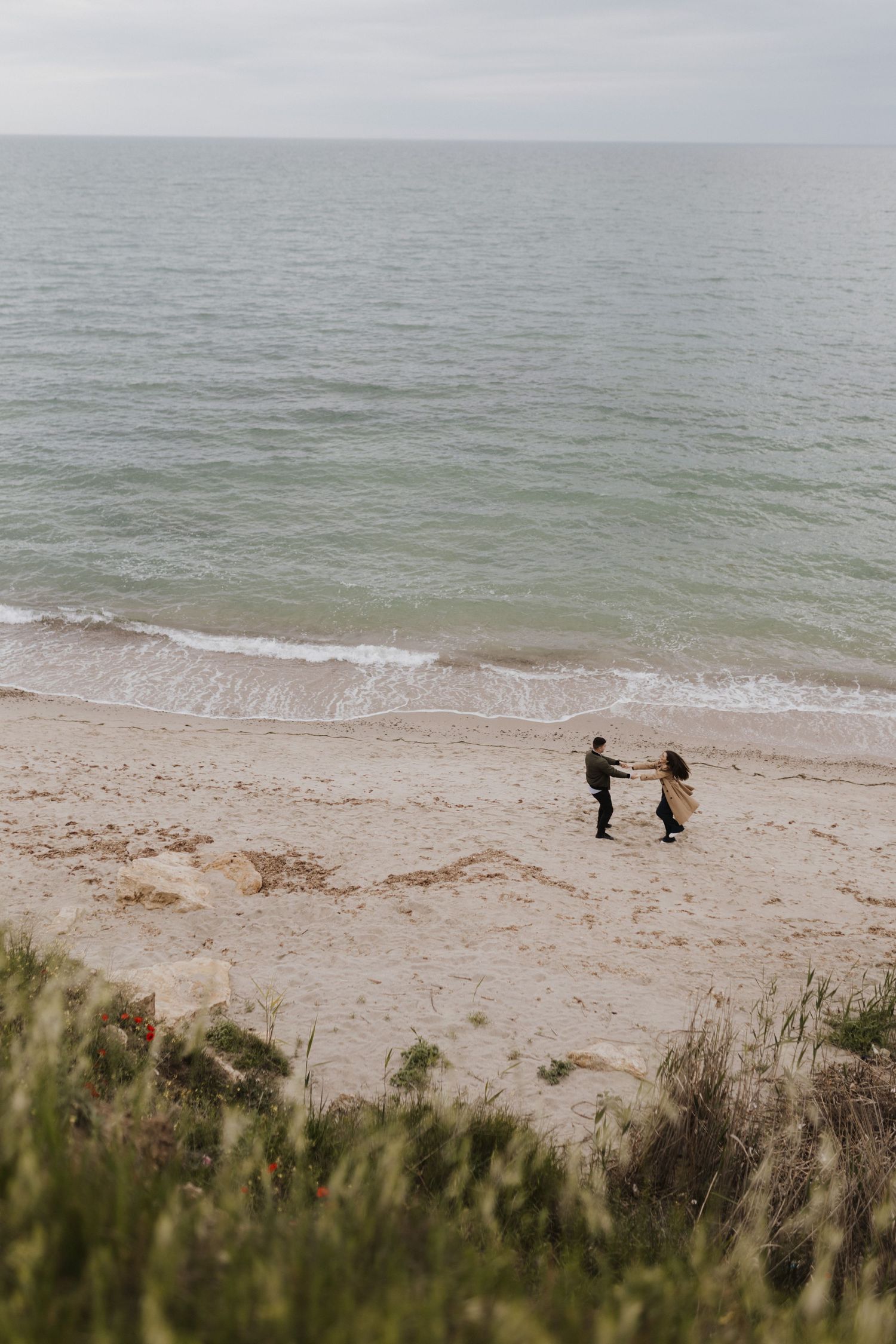 Aerial view of two figures standing together on a secluded beach.