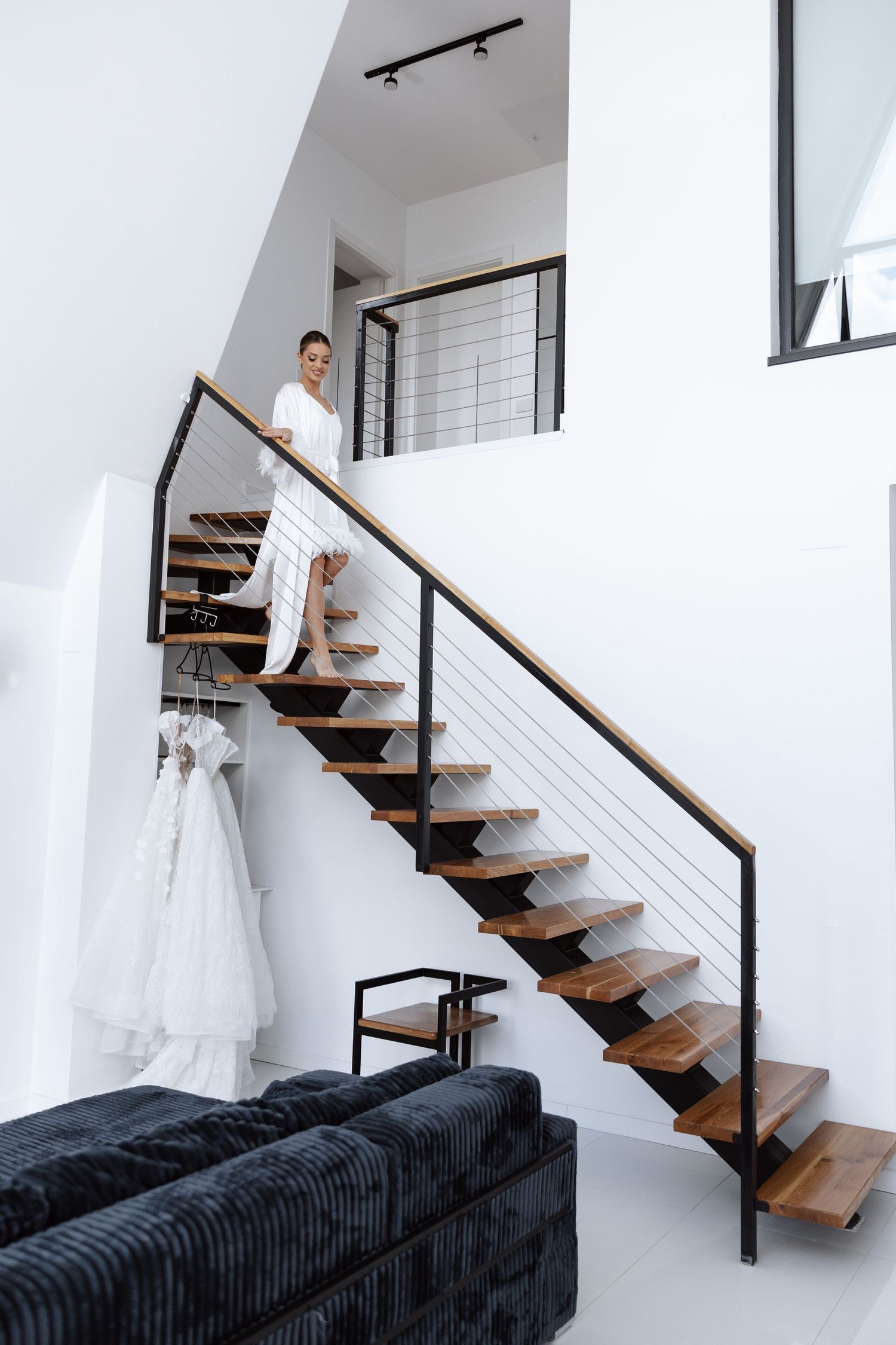 A modern staircase with wooden steps and metal railings leads upward in a bright white interior space.