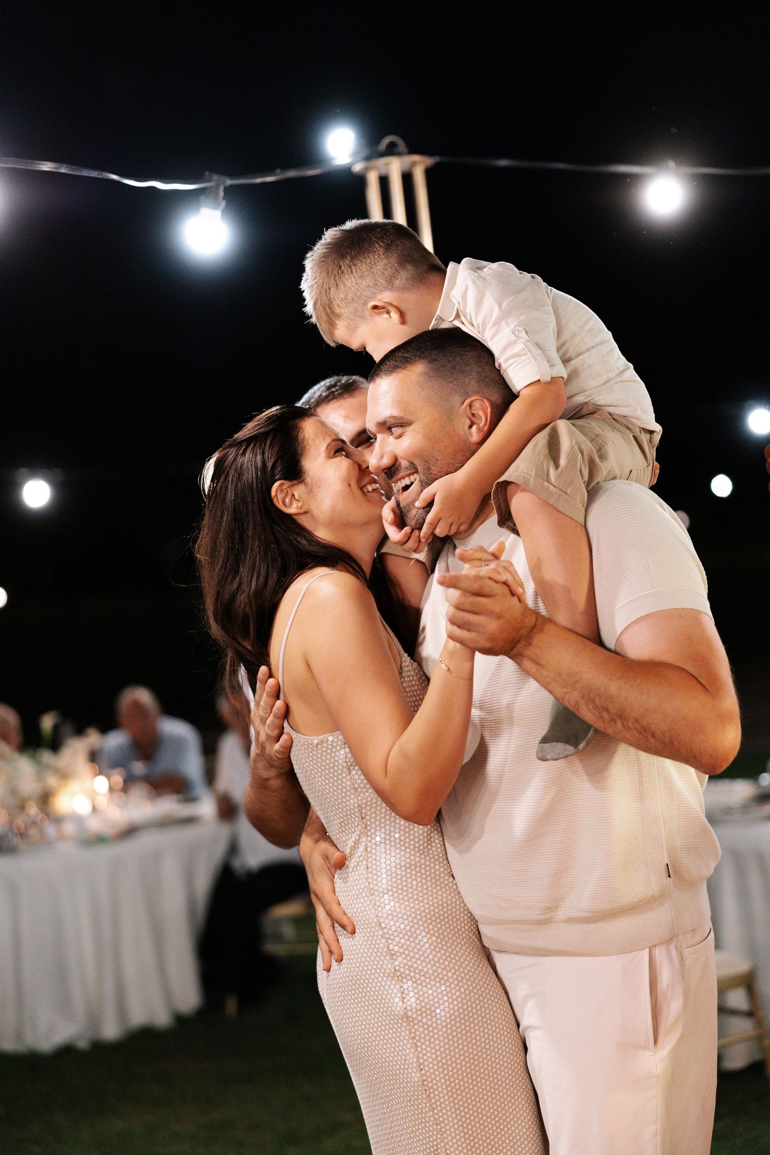 A romantic couple shares an intimate dance under evening lights at an outdoor wedding reception.