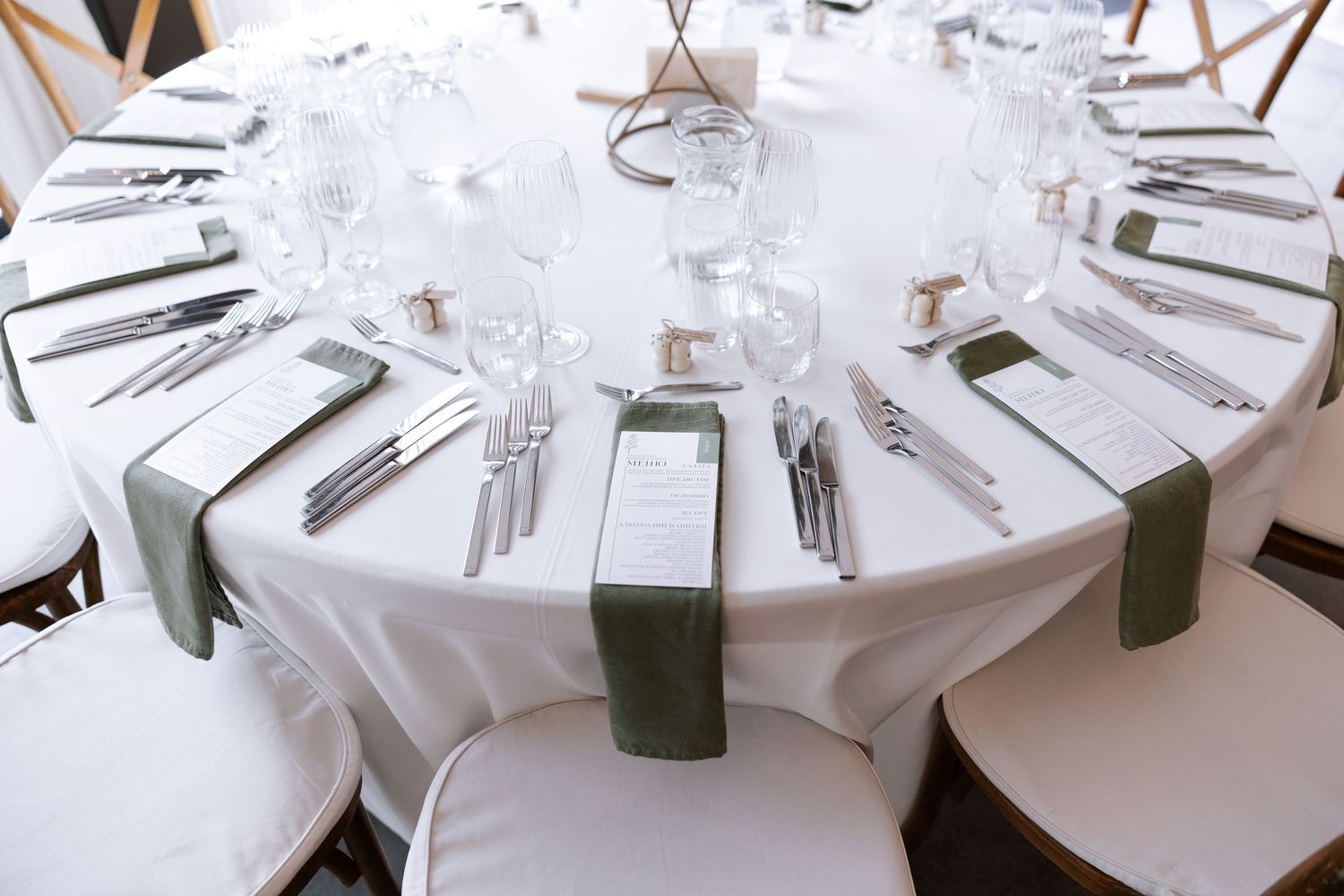 White round dining tables with crisp linens and place settings arranged in an elegant banquet hall setup.