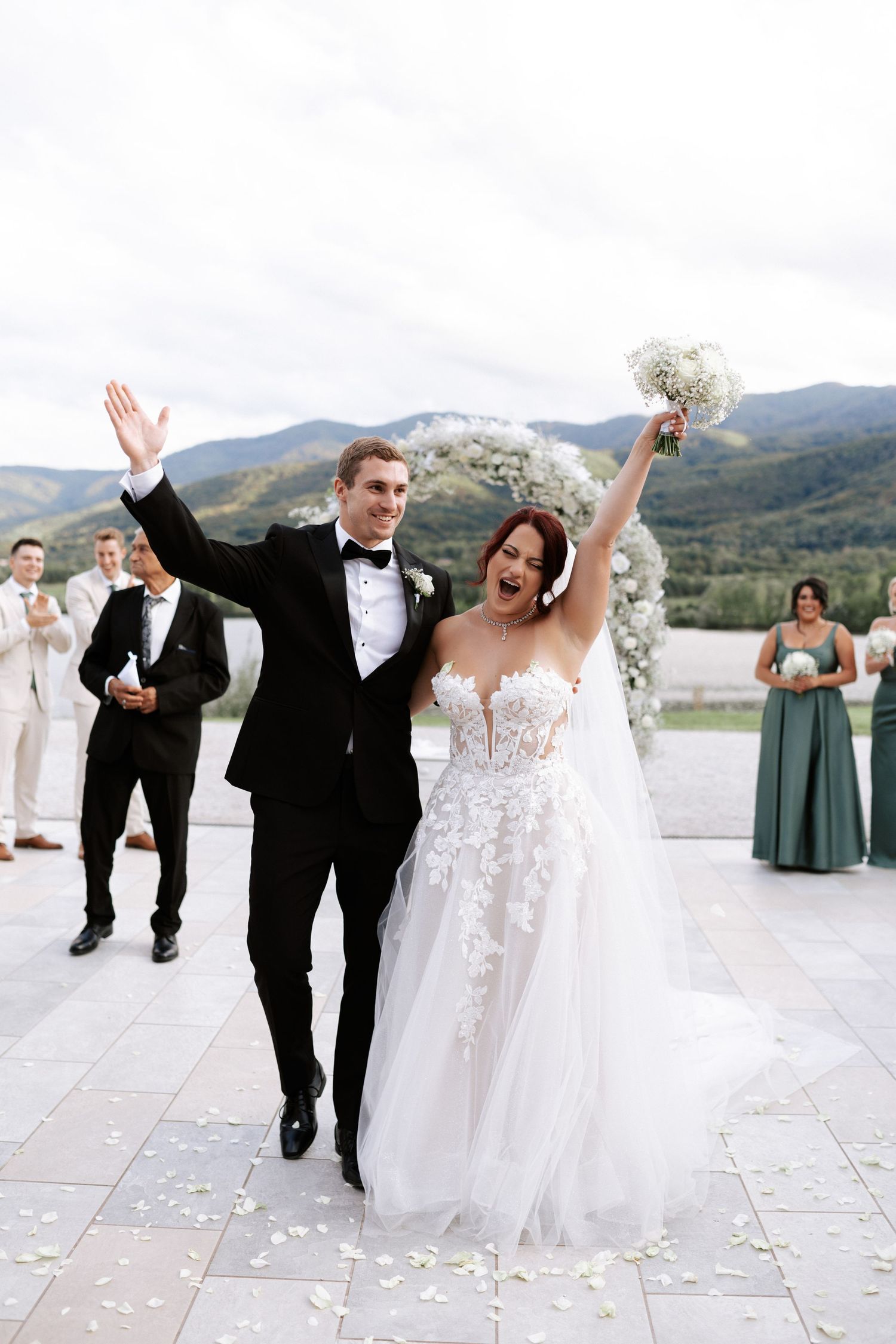 Happy couple celebrates with raised arms after wedding ceremony in mountain setting.