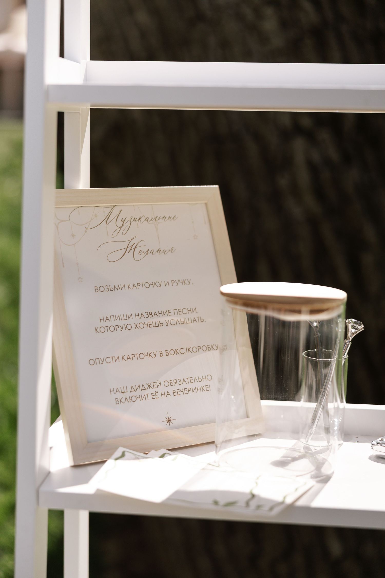 Elegant wedding place cards and menu settings arranged on a white display shelf in natural lighting.