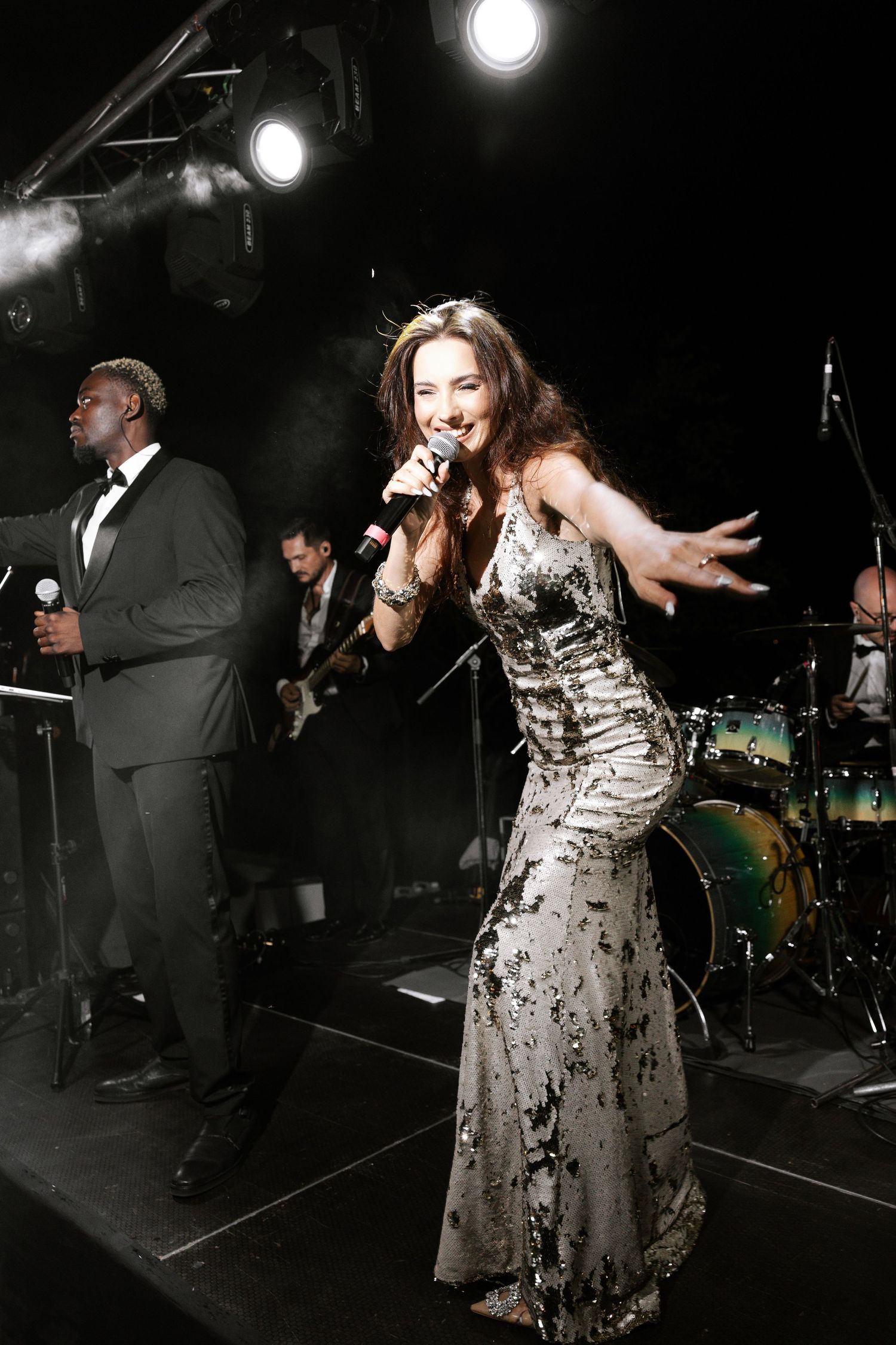 Dramatic nighttime performance with stage lighting and formal attire at wedding reception.