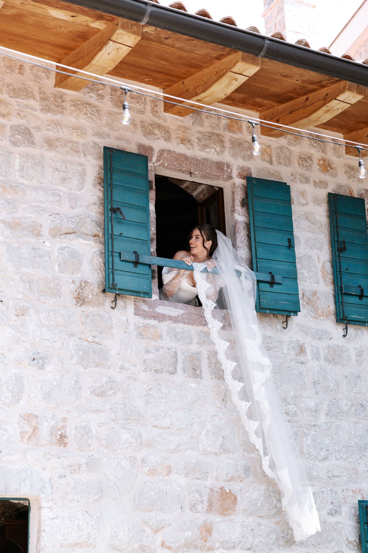 A sequence of photos showing a white wedding dress being passed through a small window of a stone building.