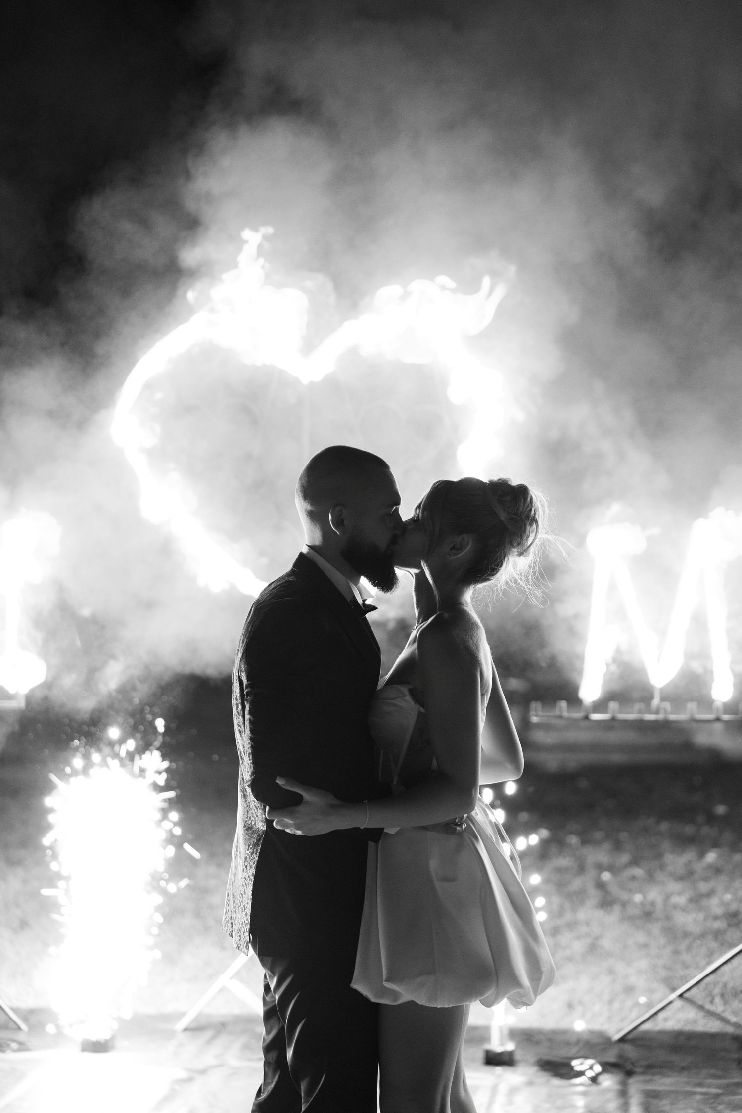 A romantic silhouette of a couple embracing against glowing light effects creating a heart shape in black and white.