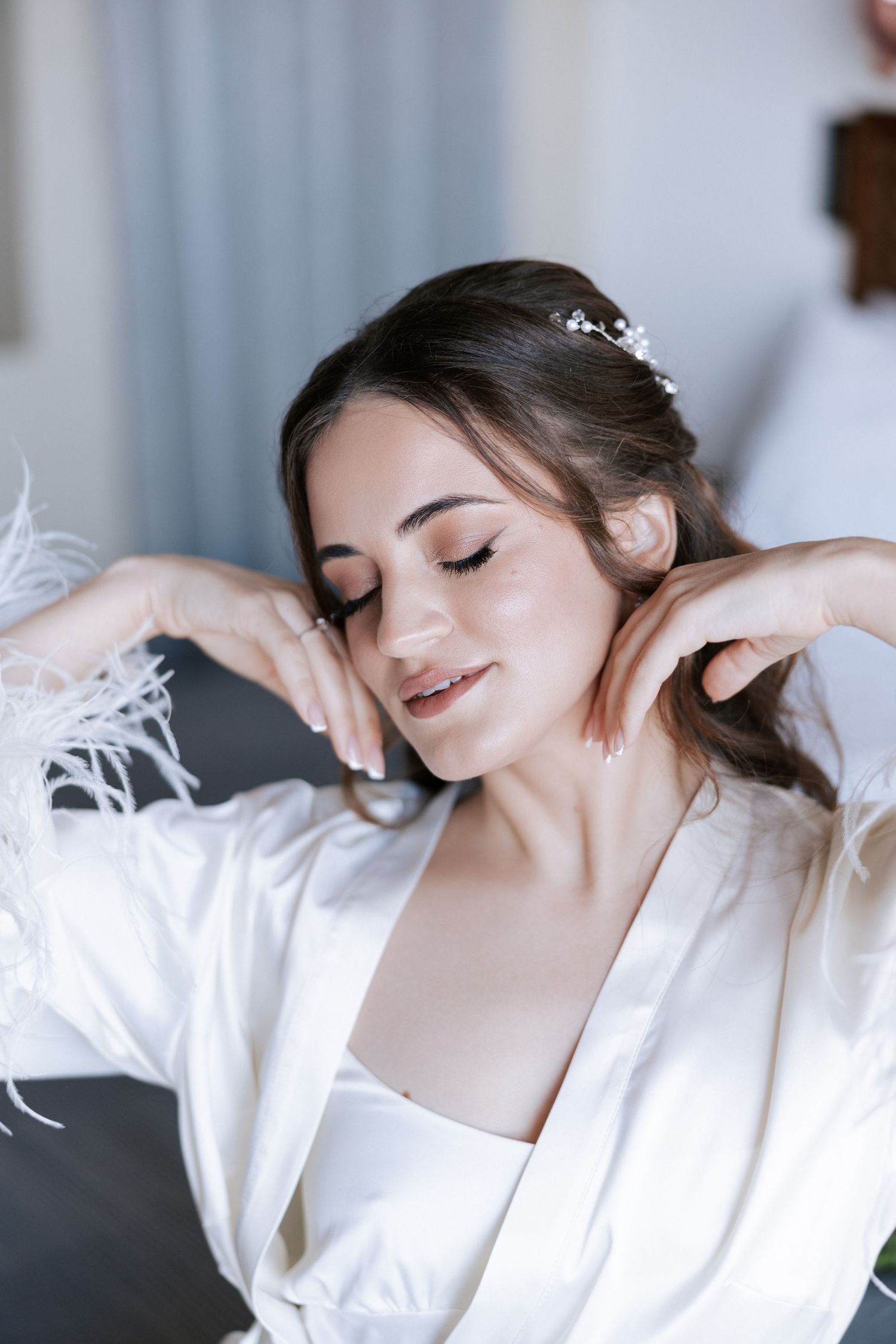 Portrait showing elegant bridal makeup and hair styling with white robe.