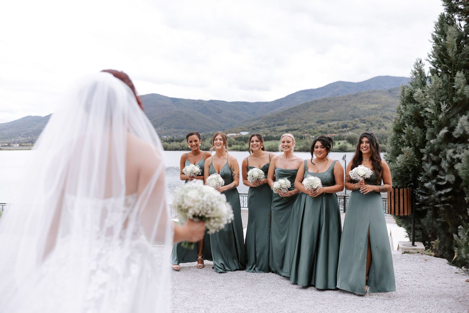 Candid wedding moment with bridesmaids in sage dresses overlooking a mountain lake.