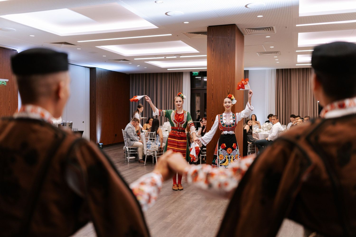 Folk dancers entertain guests with traditional performances at an indoor wedding venue.