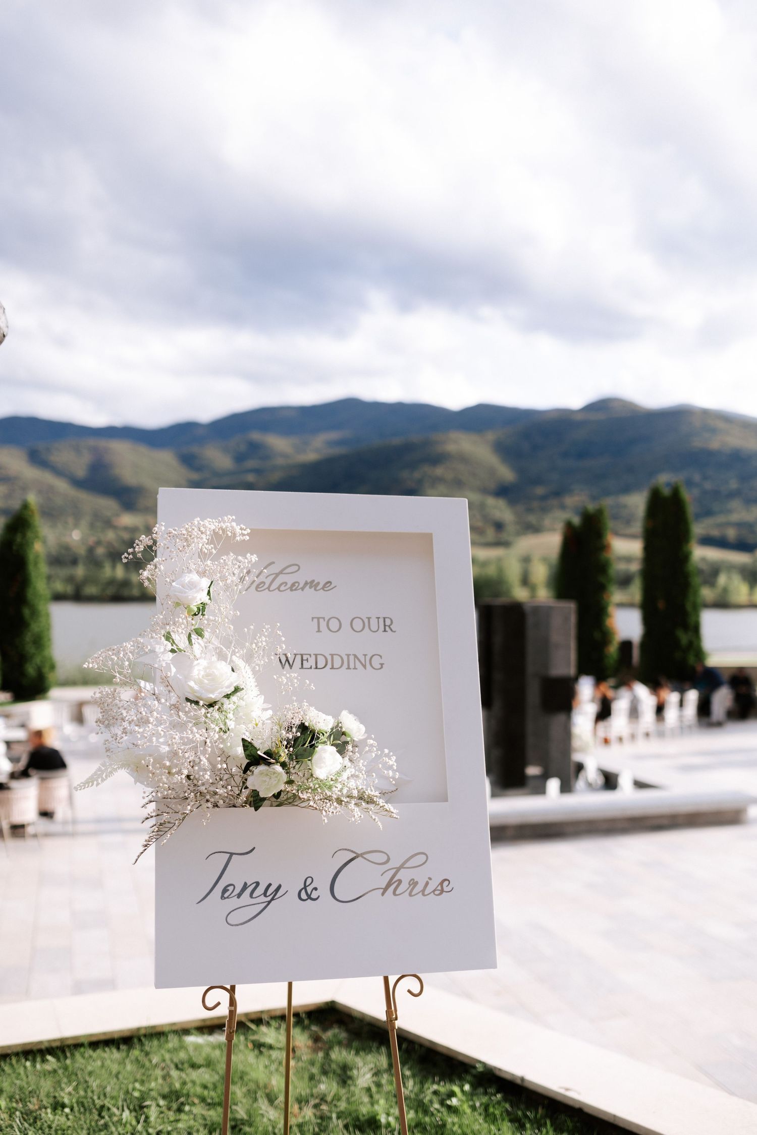 Wedding welcome sign for Jerry and Chris with white floral decorations against mountain scenery.