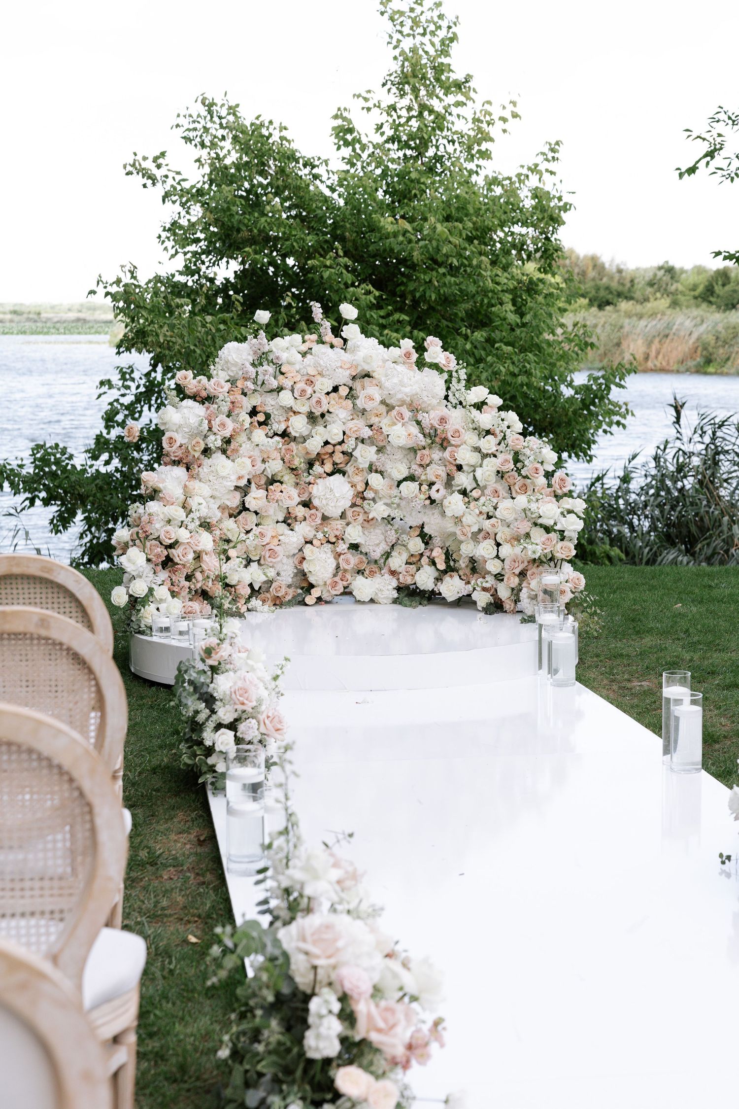 Outdoor wedding ceremony setup with luxurious white and blush floral arch arrangements.