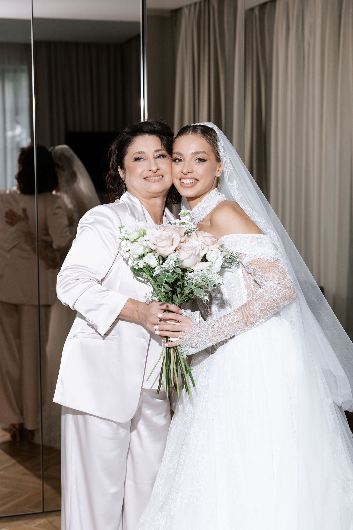 Two people share a joyful moment in elegant white wedding attire.