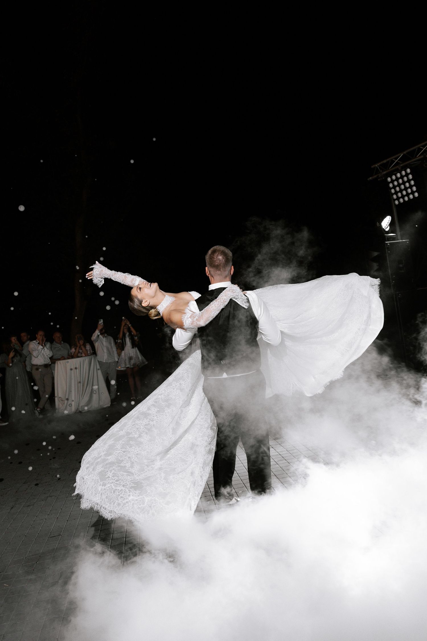 Dramatic wedding dance photos with fog effects and dramatic lighting on a dark dance floor.