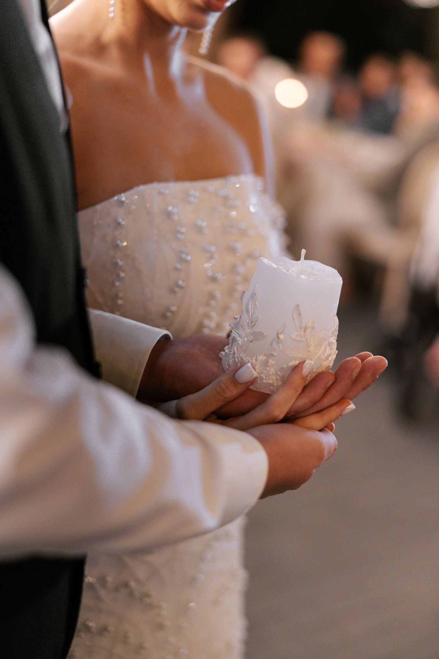 Close-up detail of a beaded white wedding dress with delicate embellishments.