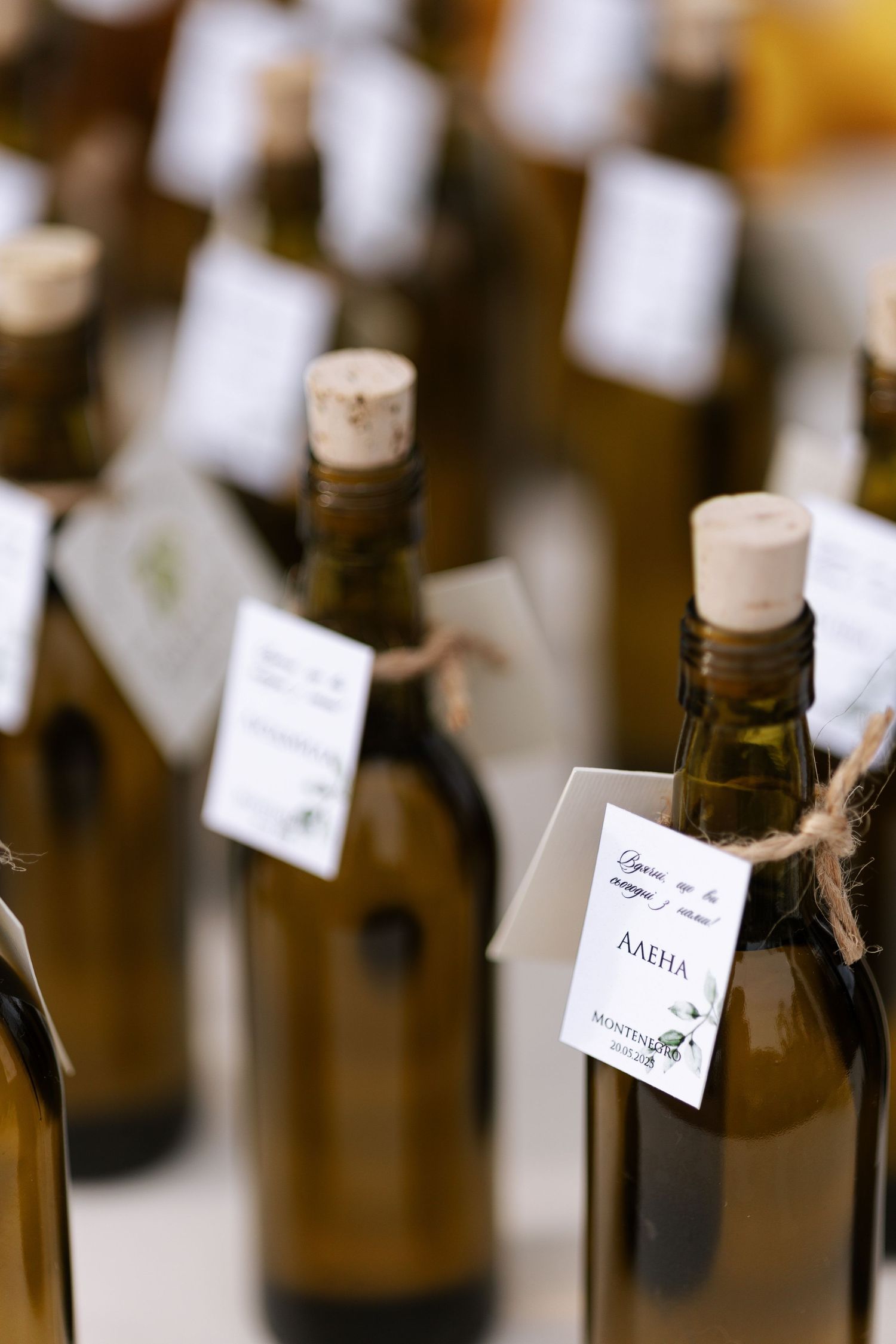 Rows of amber glass wine bottles with small white labels hanging from their necks in a dimly lit setting.